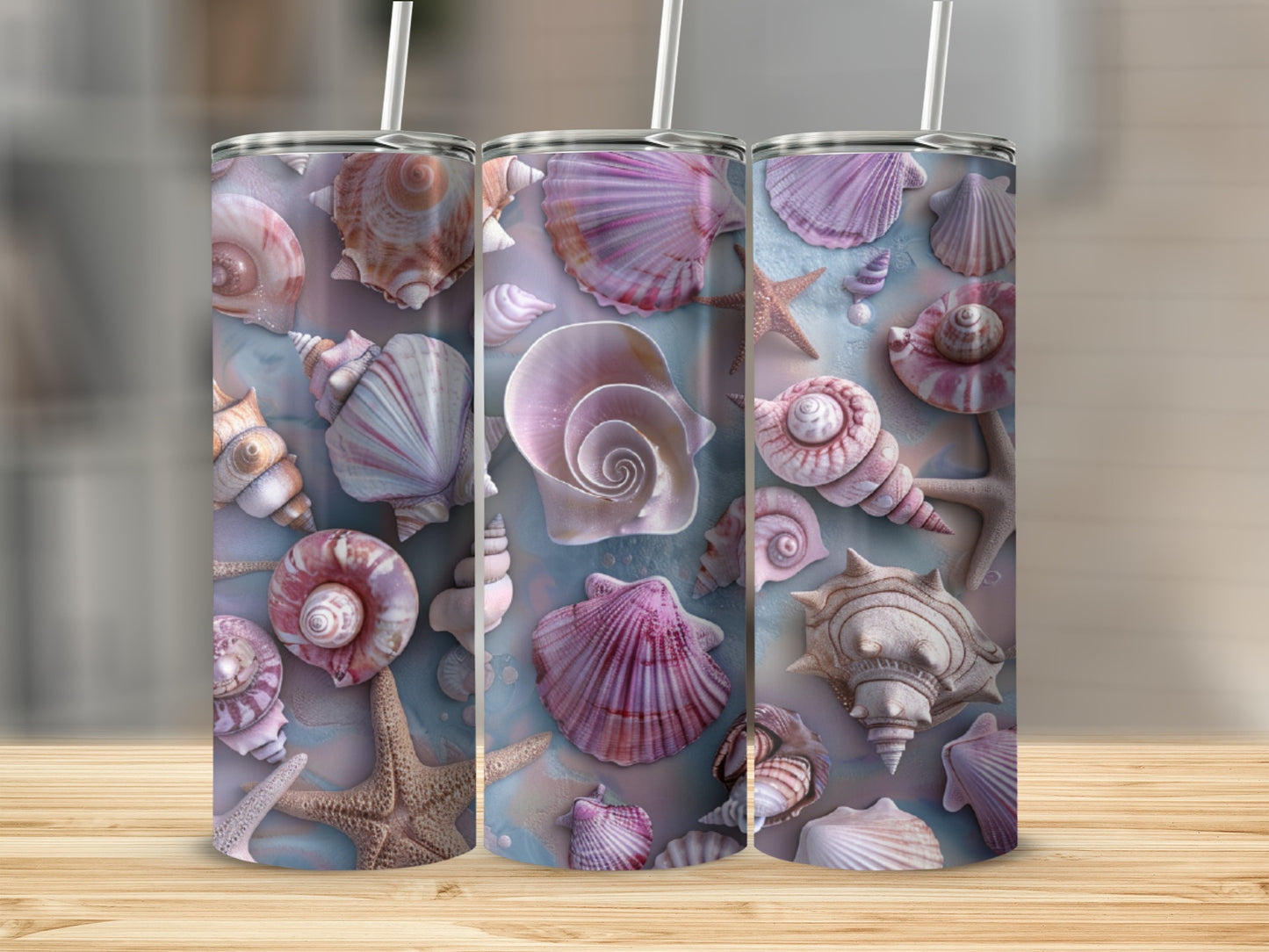 Three tumblers with seashell and starfish designs on a wooden surface.