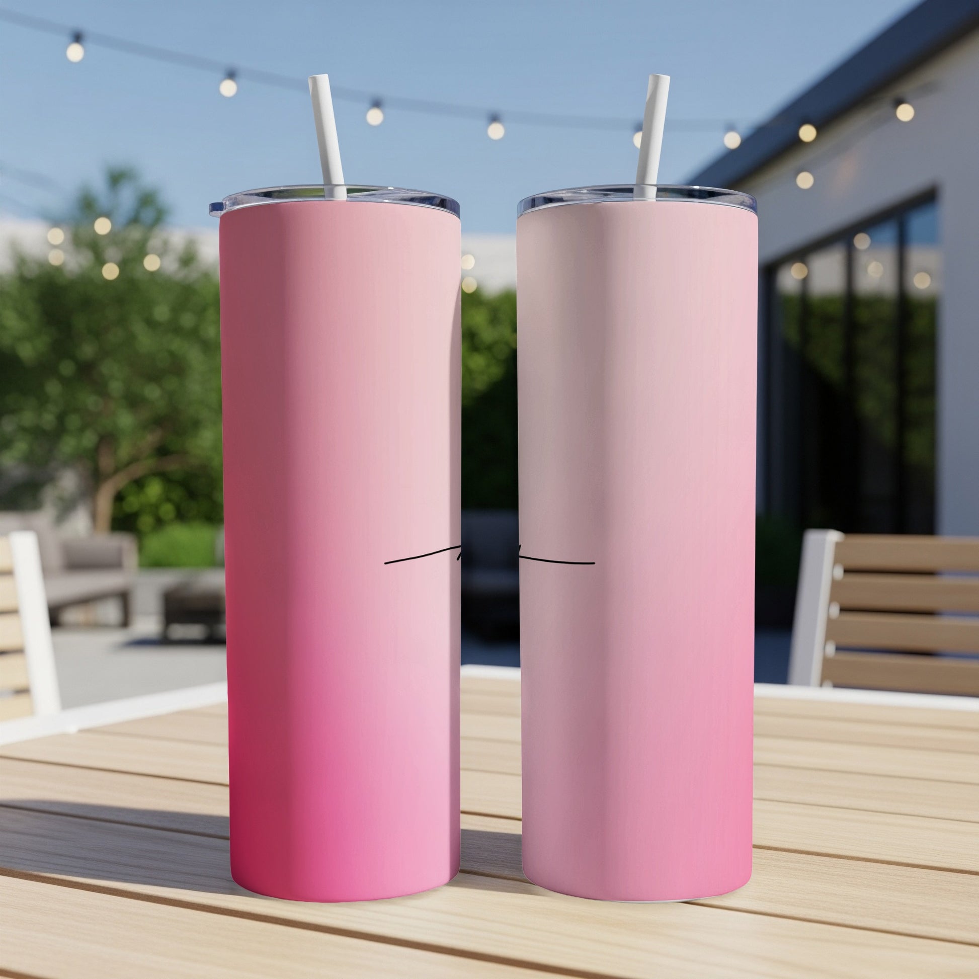 Two pink gradient tumblers with straws on a table.