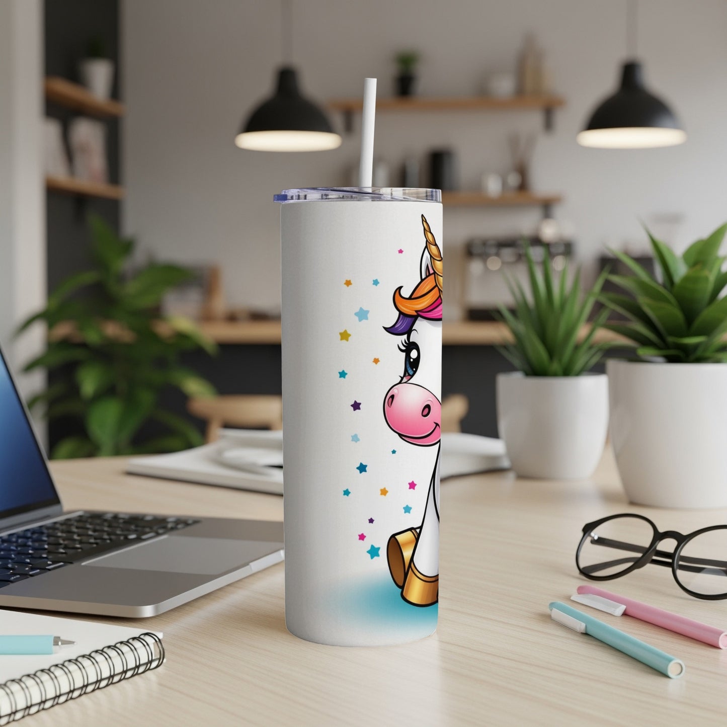 White tumbler with cartoon unicorn and colorful stars, on a desk.