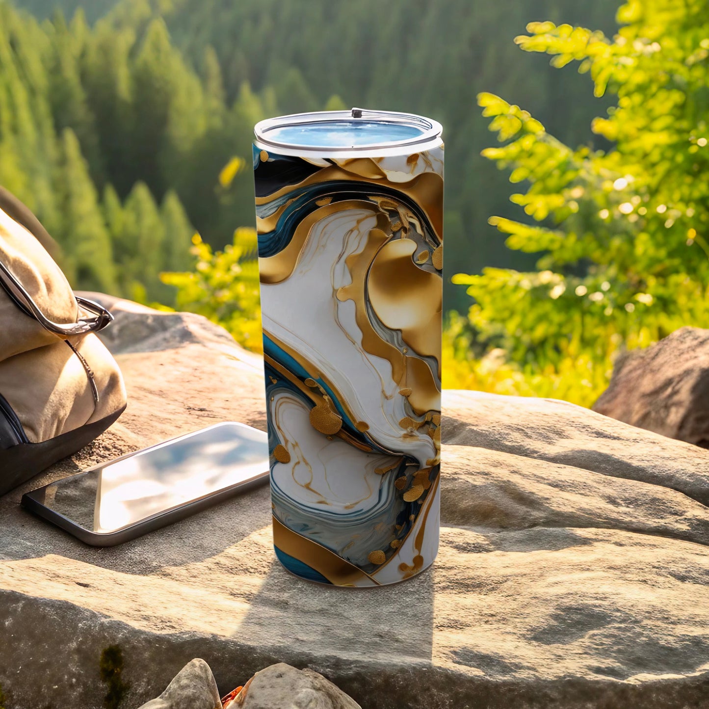Tumbler with marbled gold and white abstract design next to phone and backpack.