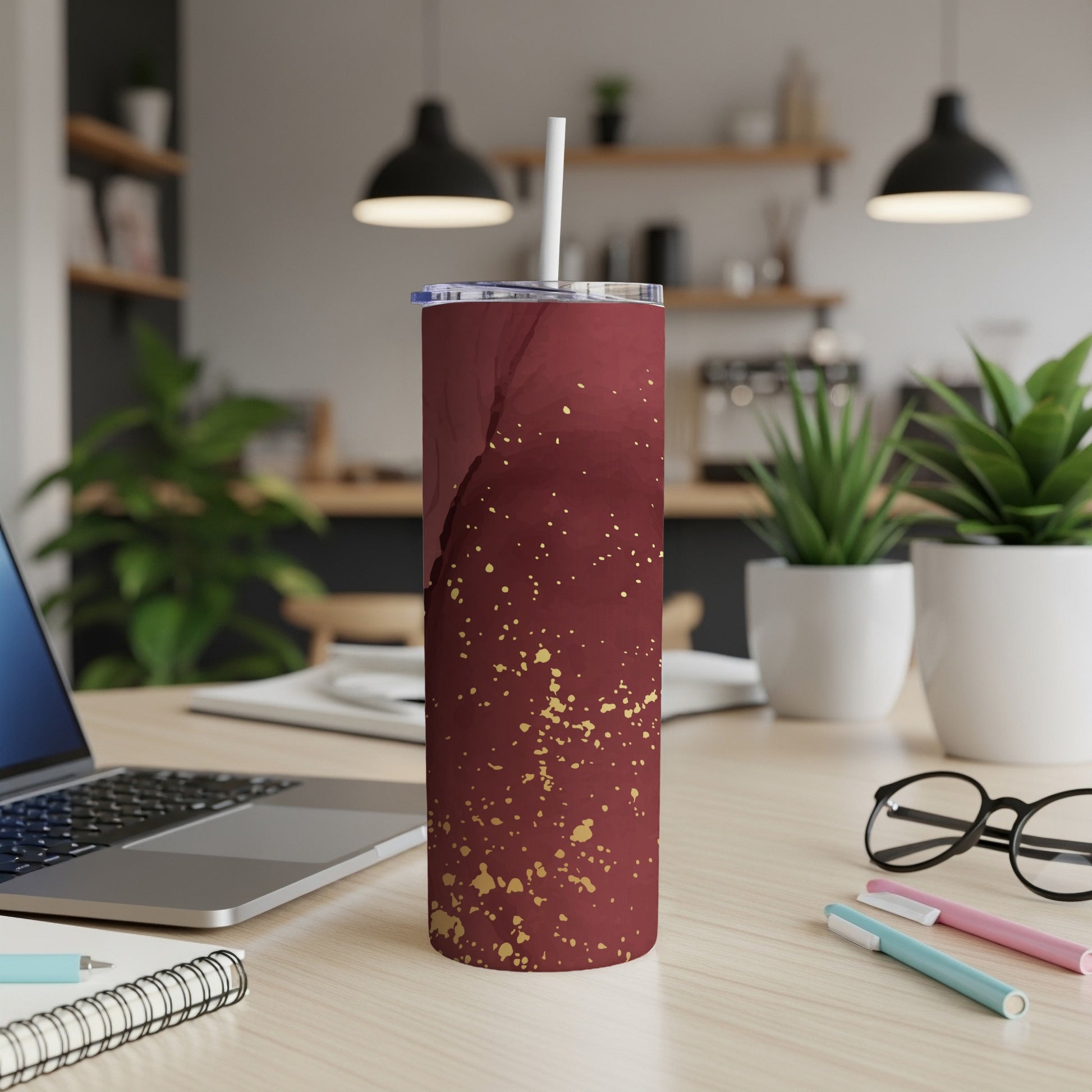 Maroon tumbler with gold speckle pattern and white lid on desk.