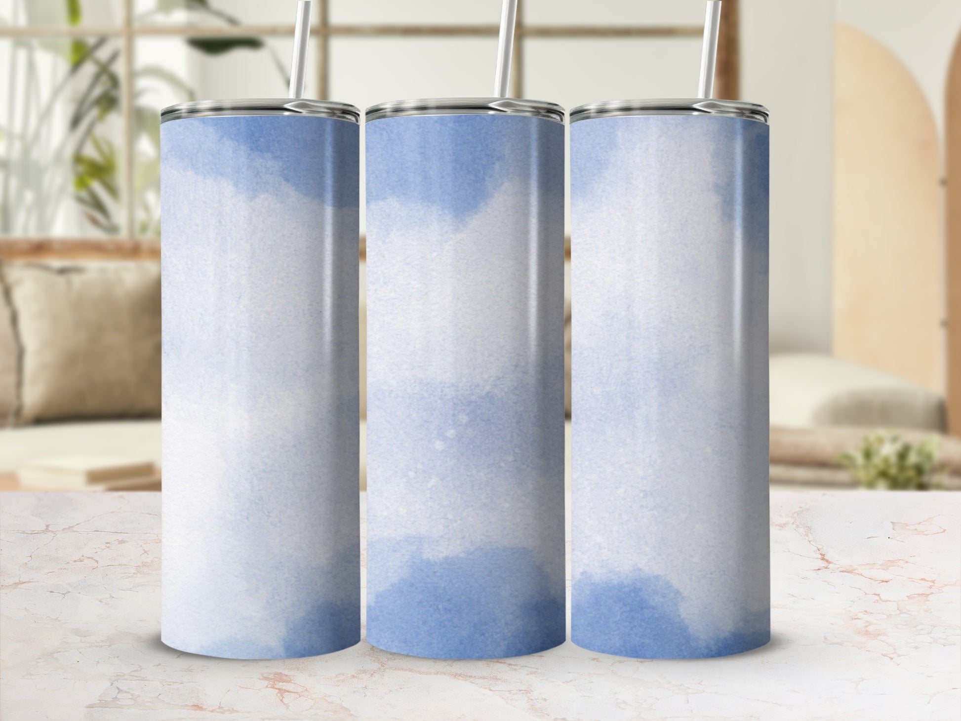 Three blue watercolor patterned tumblers with straws, displayed on a marble surface.
