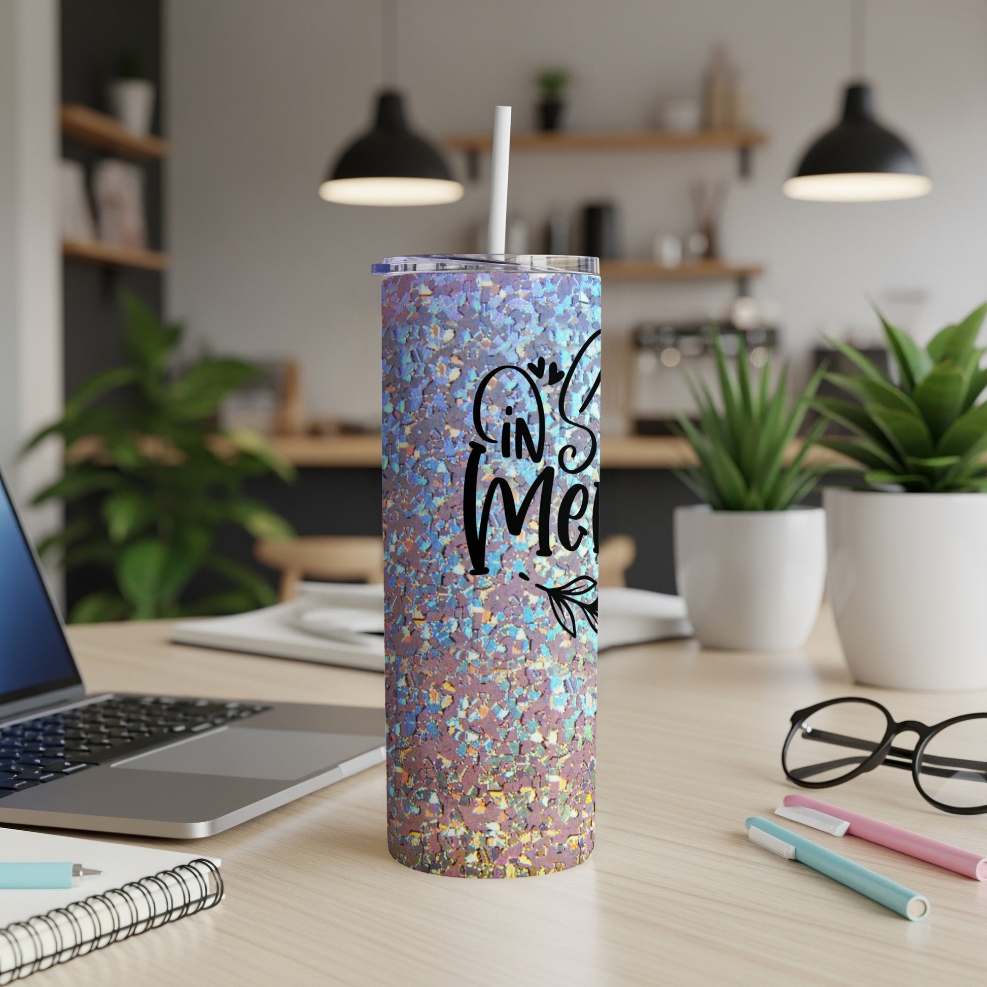 Sparkling tumbler with "In My Merry" text, on a desk with a laptop and pens.
