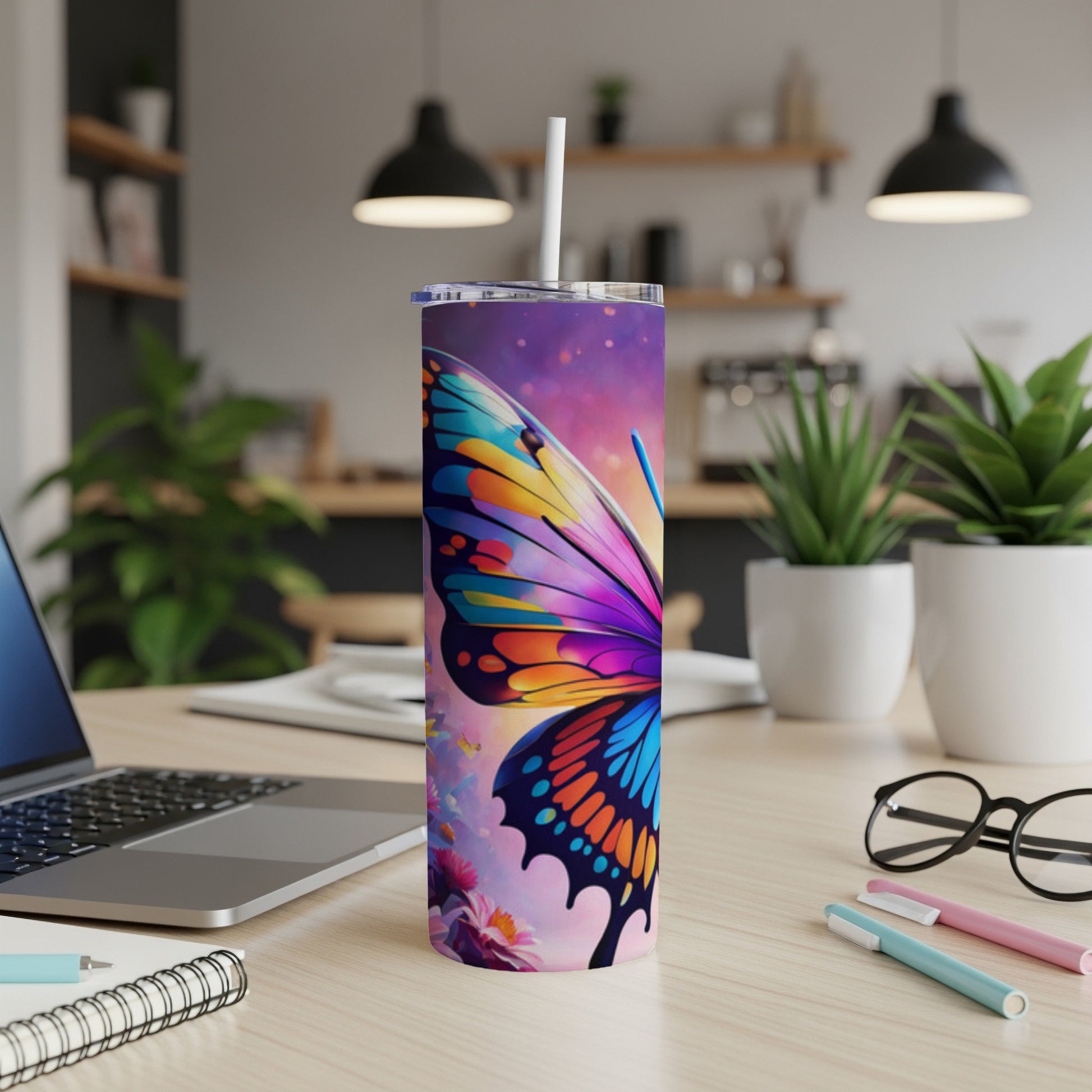 Tall tumbler with colorful butterfly design on desk next to laptop.