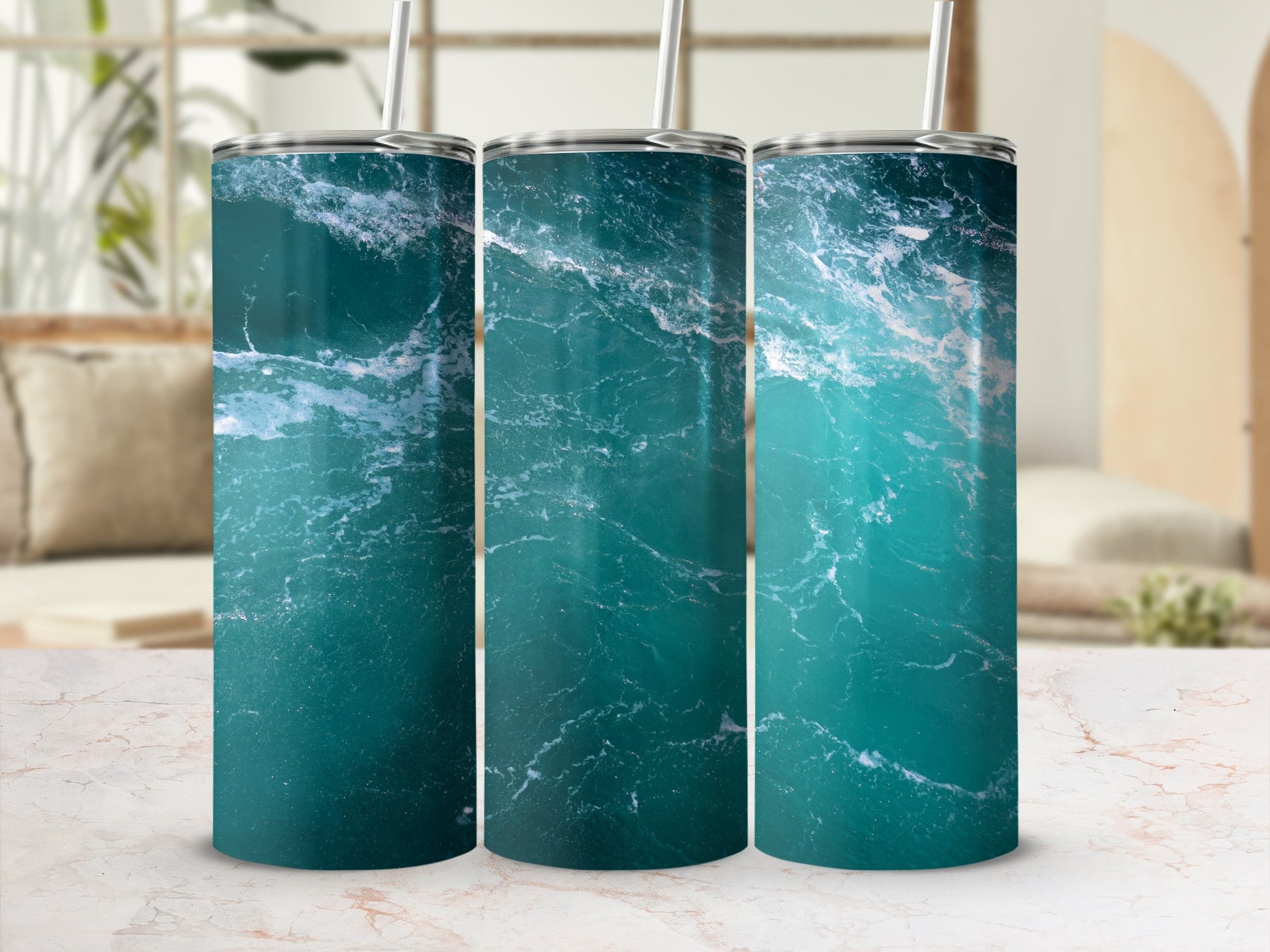 Three tumblers with a blue ocean wave design on a marbled surface.