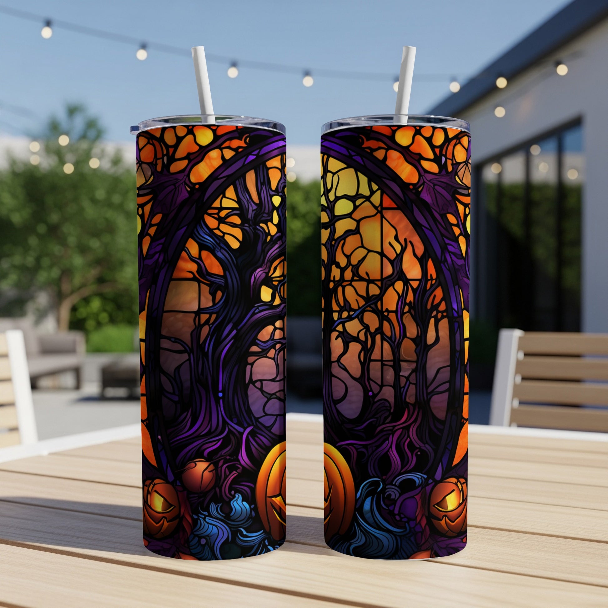 Two Halloween-themed tumblers with jack-o'-lanterns and dark trees on an outdoor table.