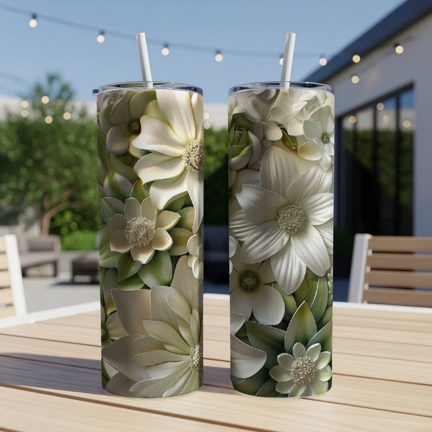 Two white and green floral pattern tumblers with straws on a wooden table.
