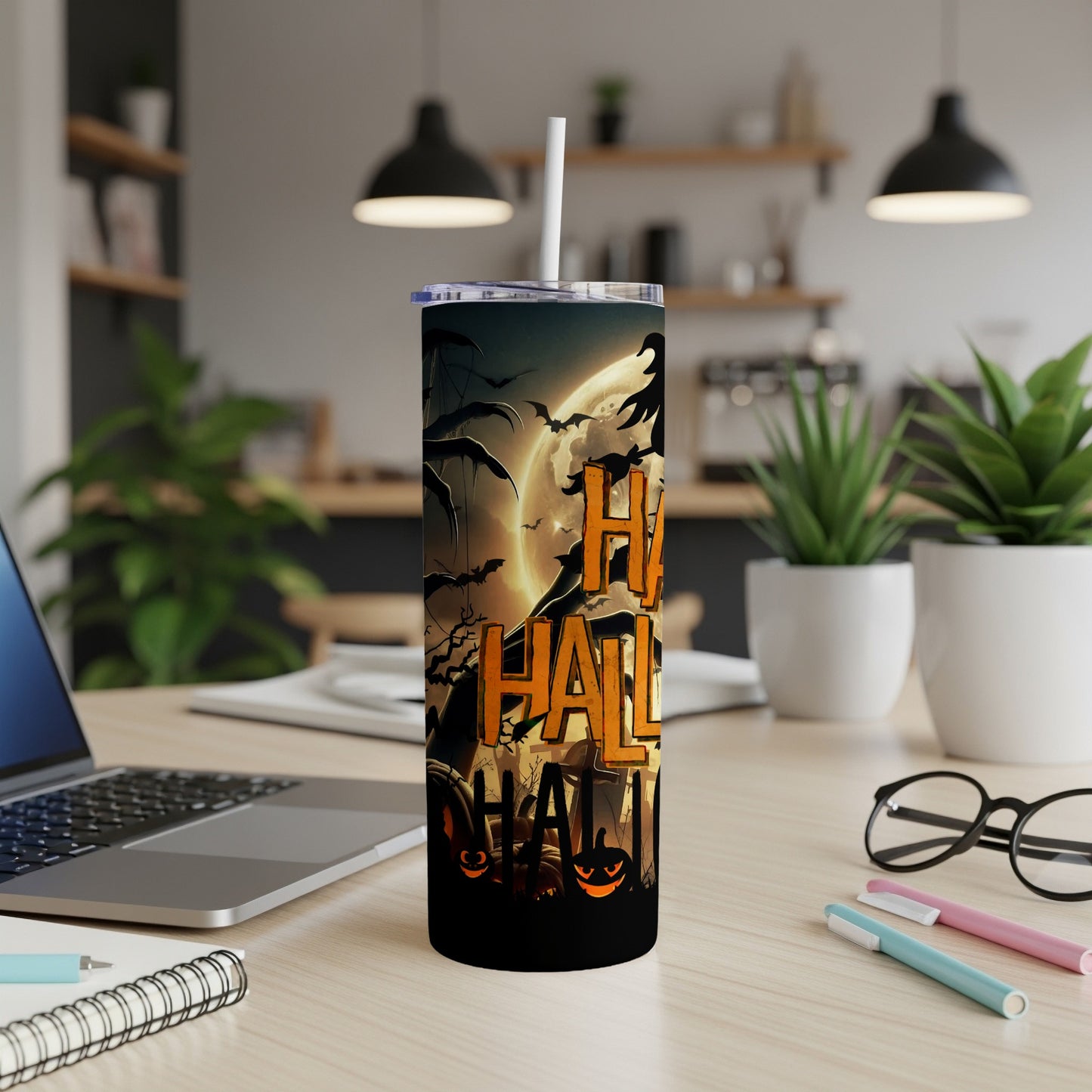 Halloween tumbler with pumpkins, bats, and spooky graphics on a desk.