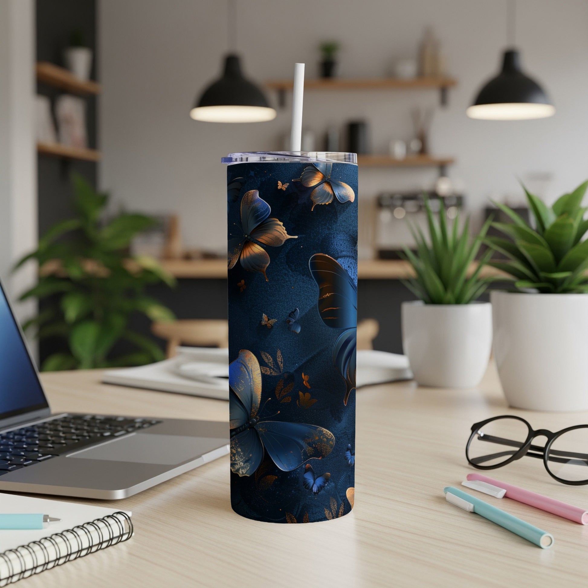 Blue and gold patterned tumbler with butterflies on a desk.