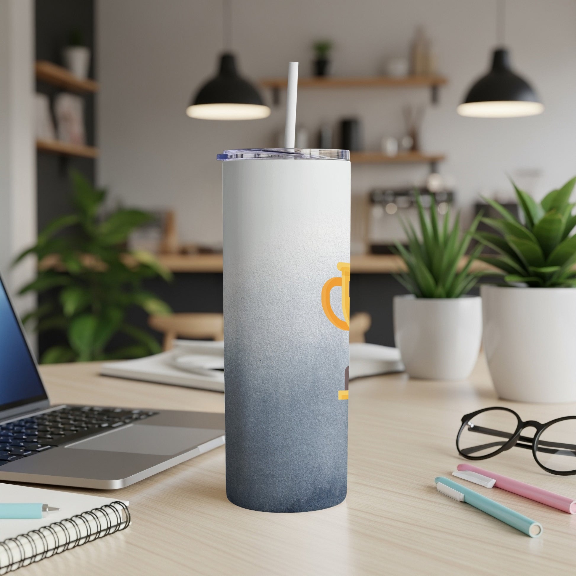 Gradient tumbler with orange text on a desk next to a laptop.