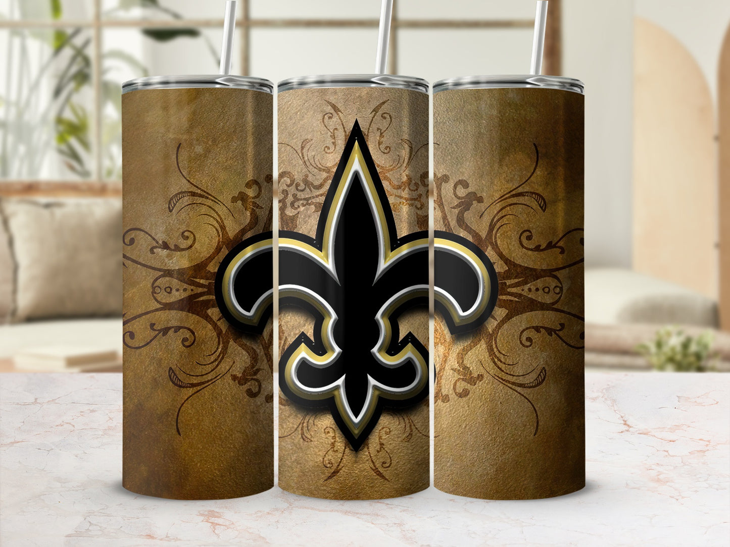 Three tumblers with New Orleans Saints fleur-de-lis logo on textured gold background.
