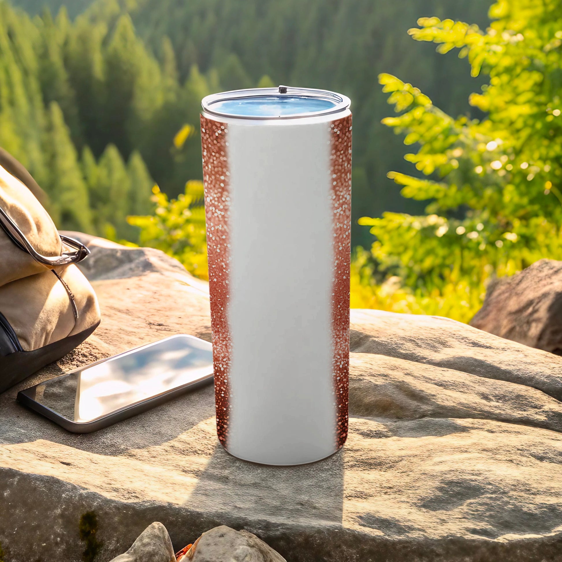 White and rose gold glitter tumbler with a blue lid on a rock.