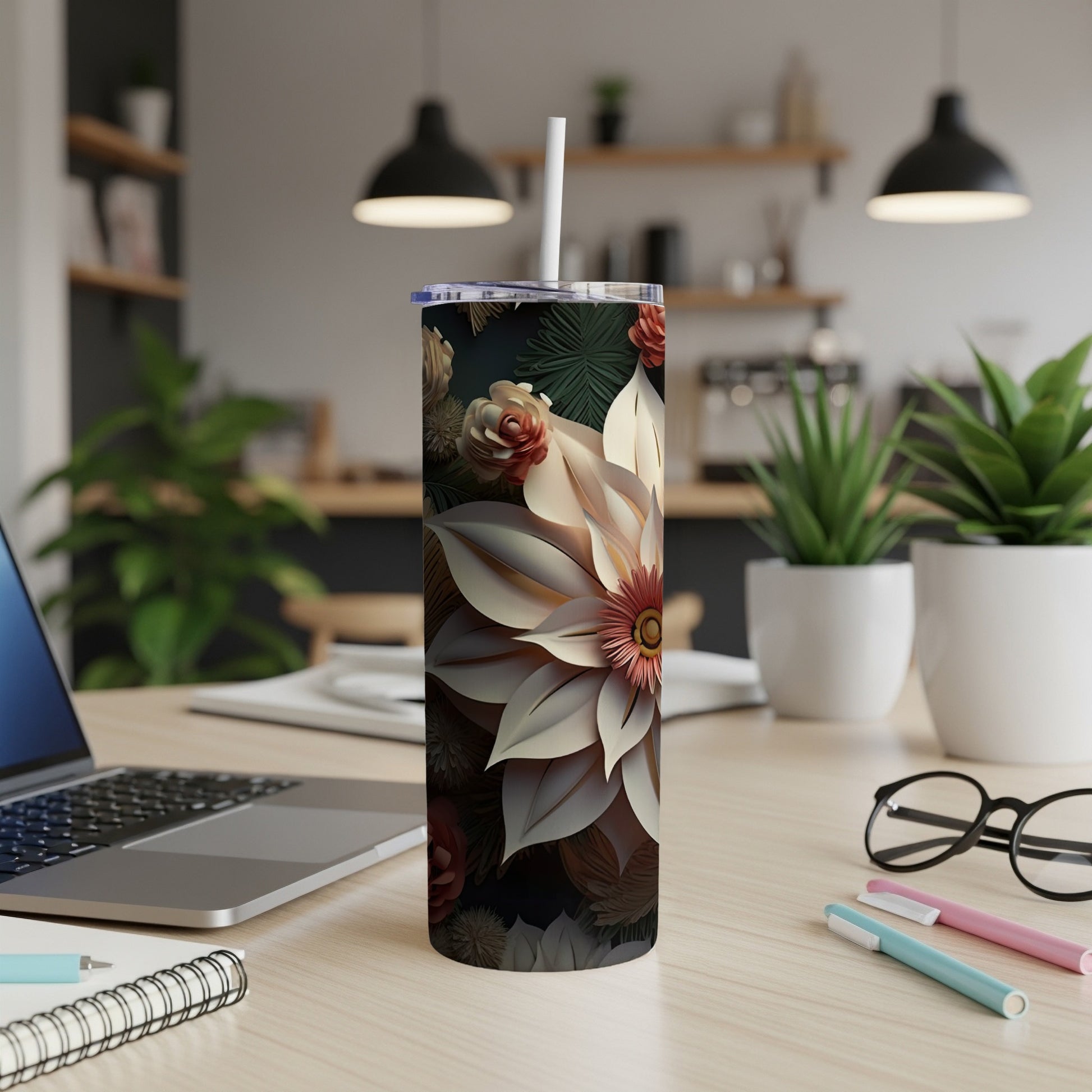 Tall floral tumbler with a white straw on a desk next to a laptop.