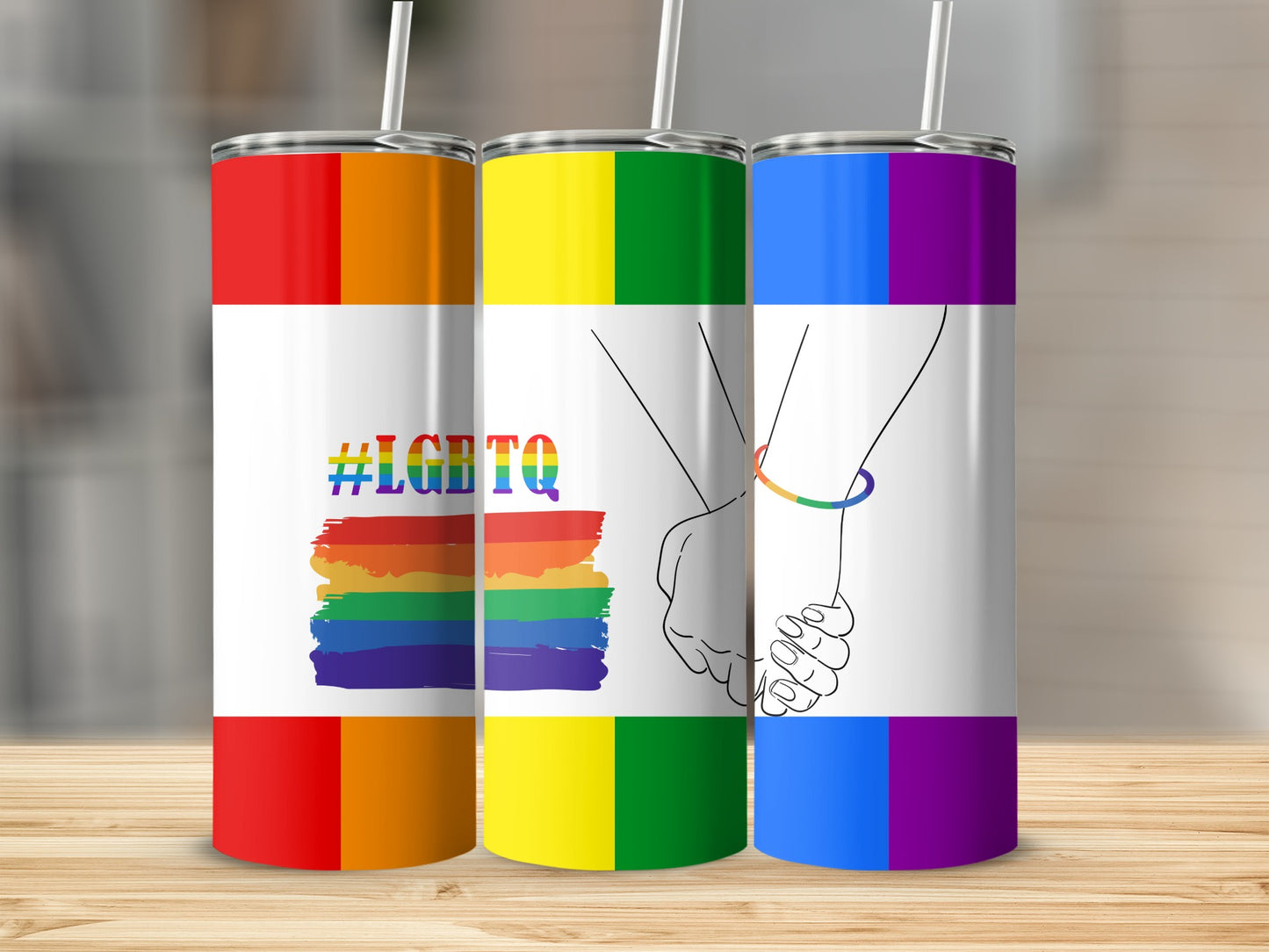 Three tumblers with rainbow and LGBTQ+ pride flag designs.