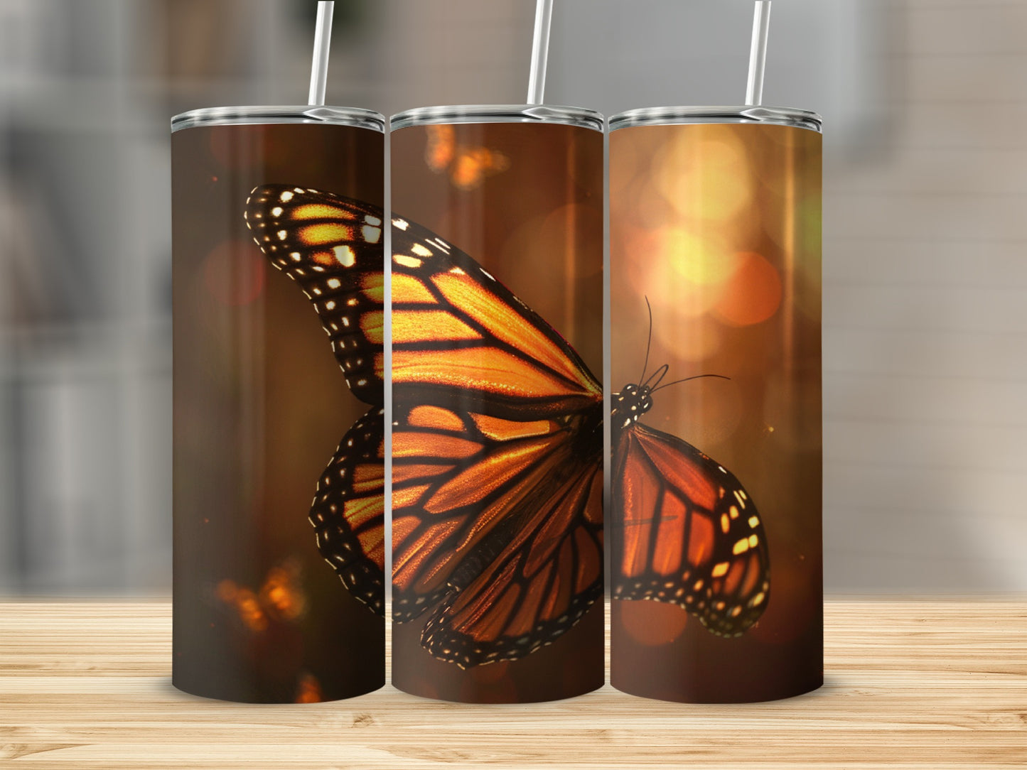Three tumblers featuring a monarch butterfly against a warm, bokeh background.