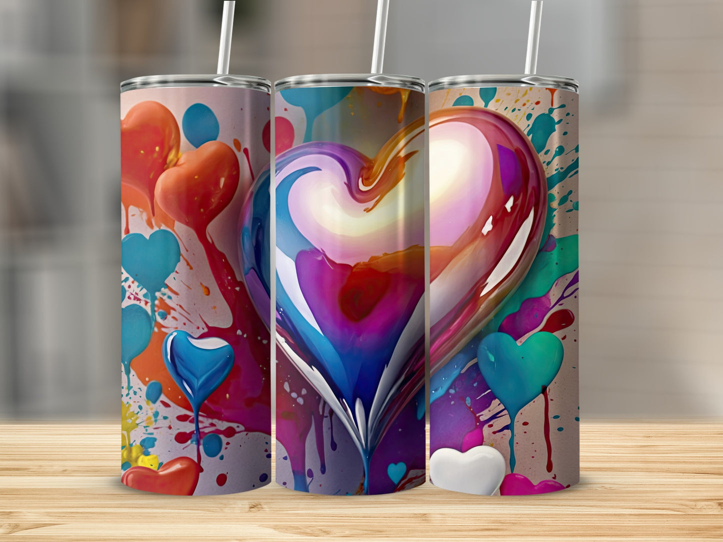 Three tumblers with heart designs and colorful paint splatters.