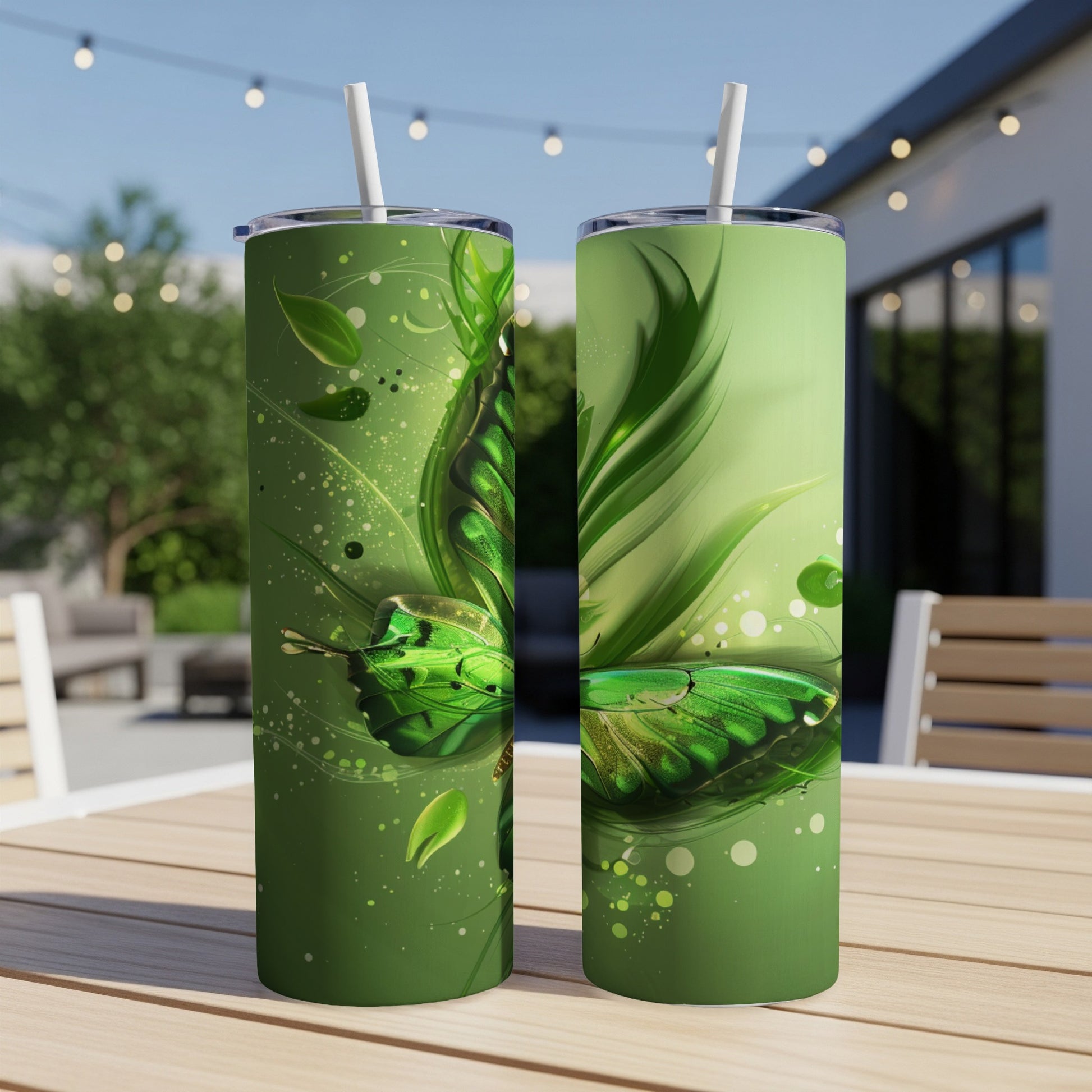 Green butterfly art on two tumblers with straws on an outdoor table.