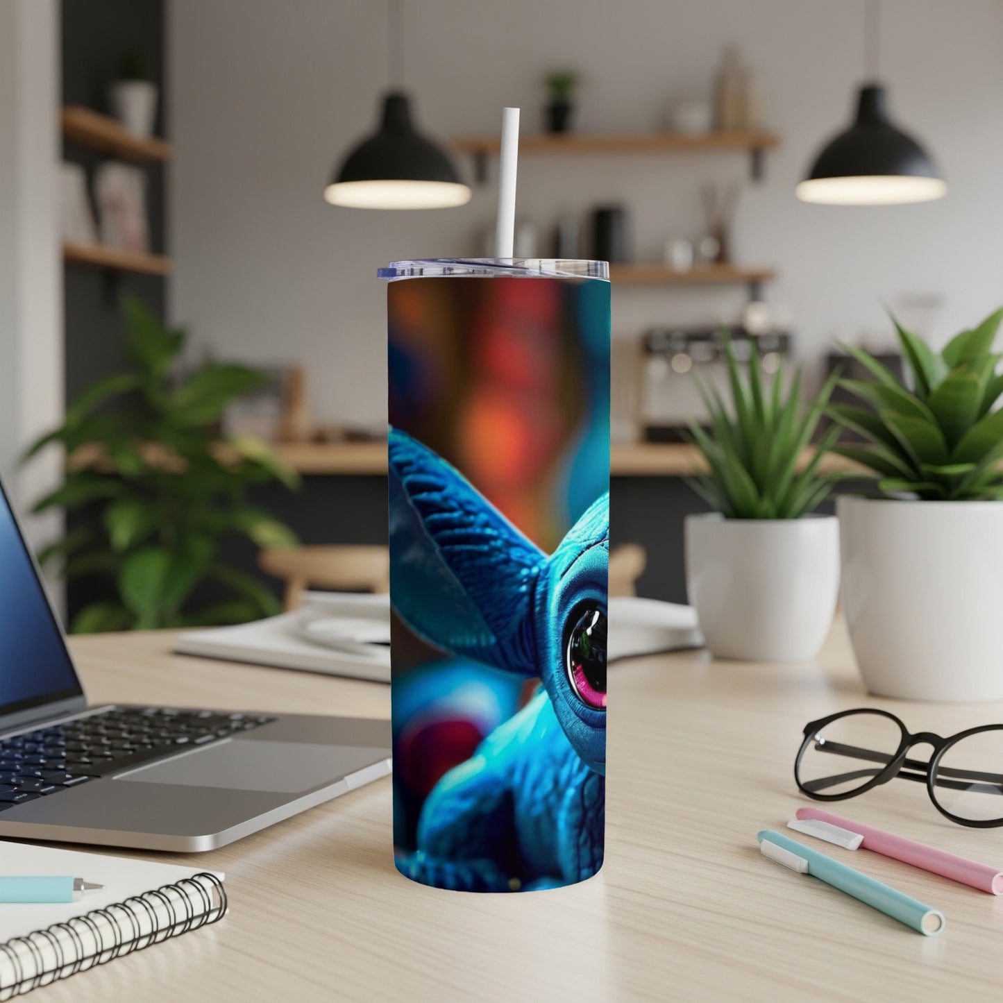 Blue alien creature tumbler with straw on a desk.