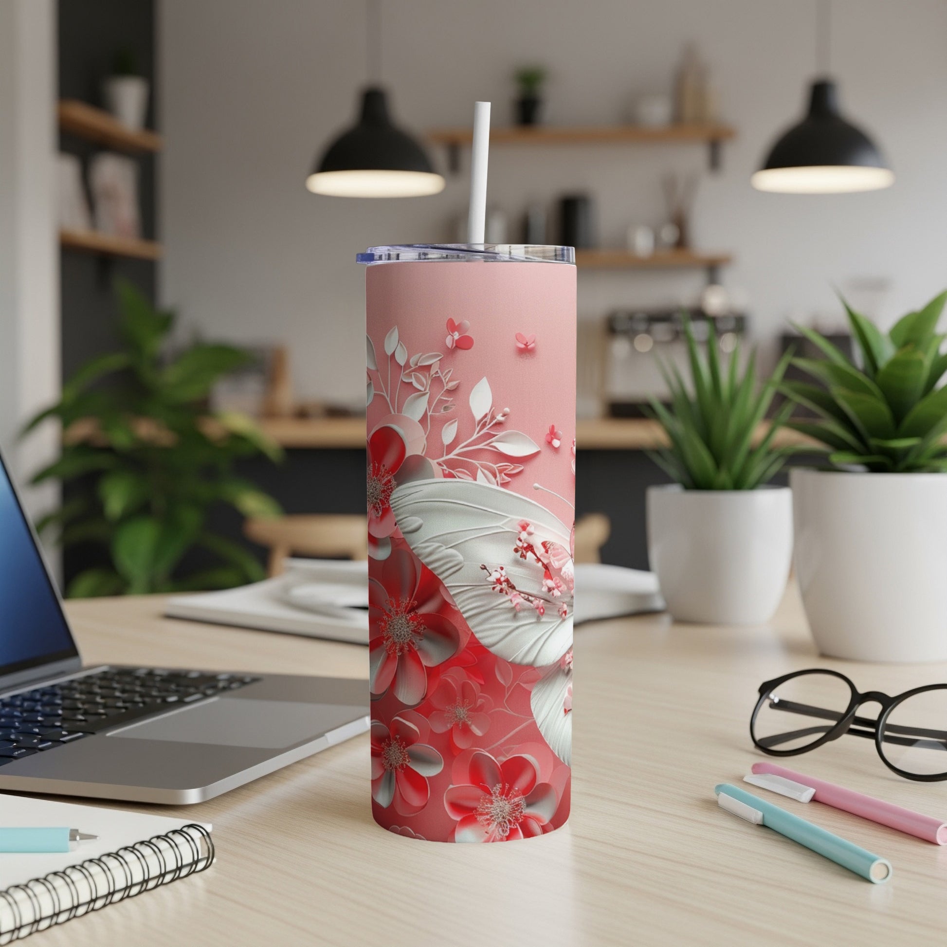 Pink tumbler with white butterfly and floral design on desk.