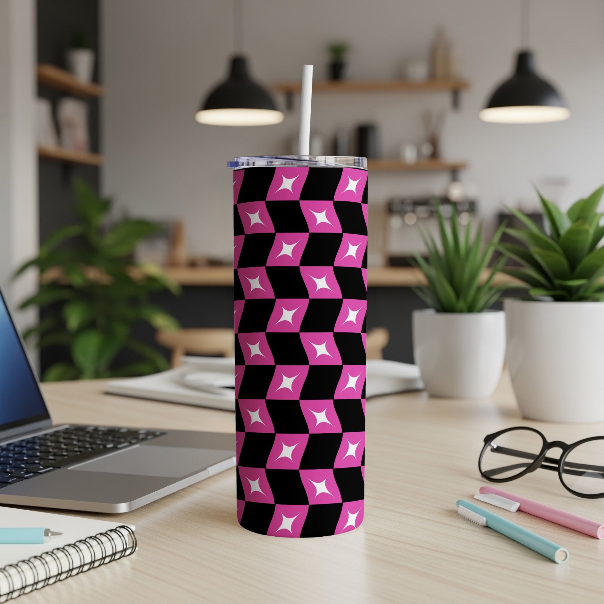 Pink and black geometric patterned tumbler on a desk with a laptop.