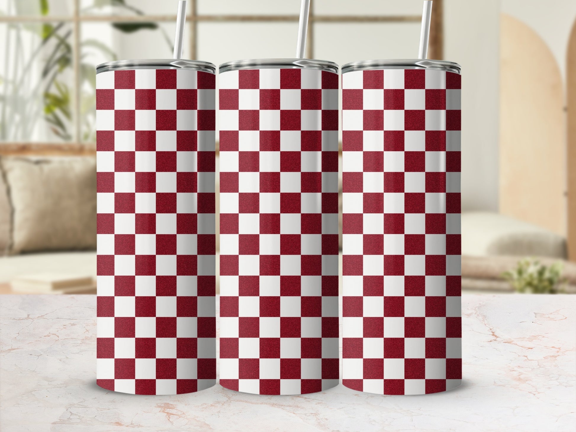 Three red and white checkered tumblers with straws on a marbled surface.