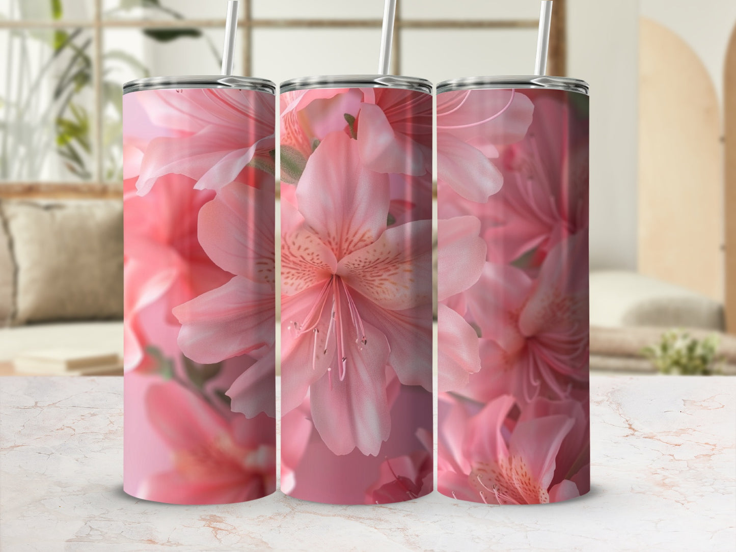 Three pink floral tumblers with straws on a marble surface.