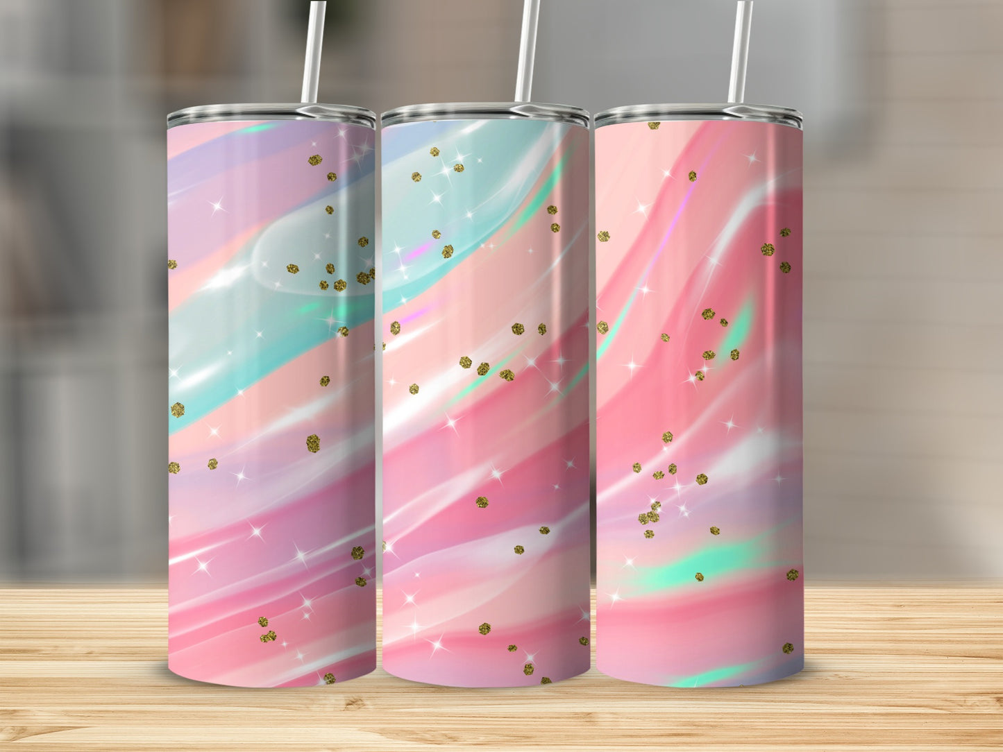 Three tumblers with pastel marble, glitter, and starburst designs on a wooden surface.