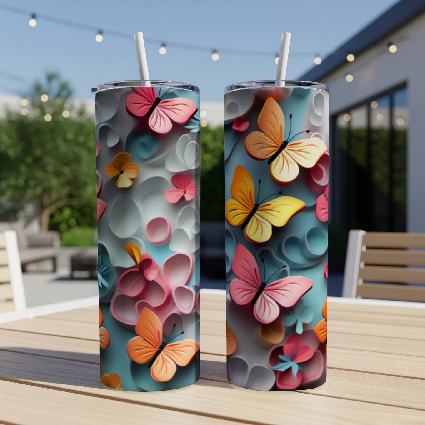 Two tumblers with a butterfly and floral design, set on a table outdoors.
