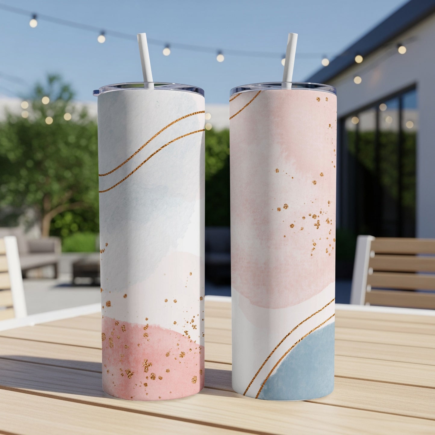 Two tumblers with watercolor abstract designs of pink, blue, and gold glitter.