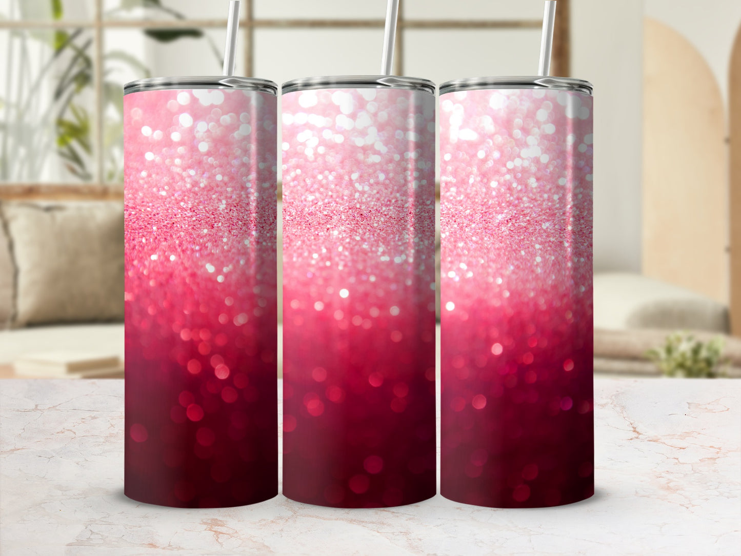 Three pink glitter tumblers with straws on a marble countertop.