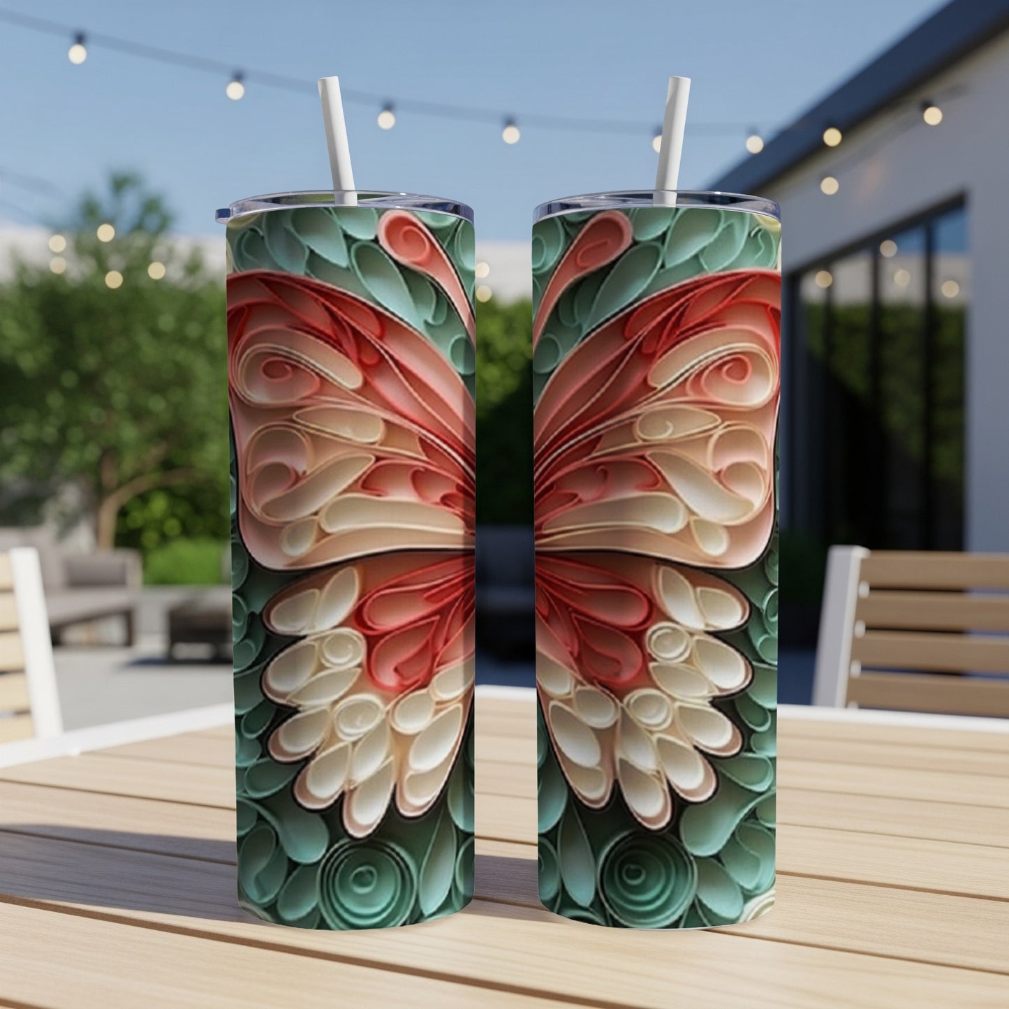 Two tumblers with a coral and teal butterfly wing design on a patio table.
