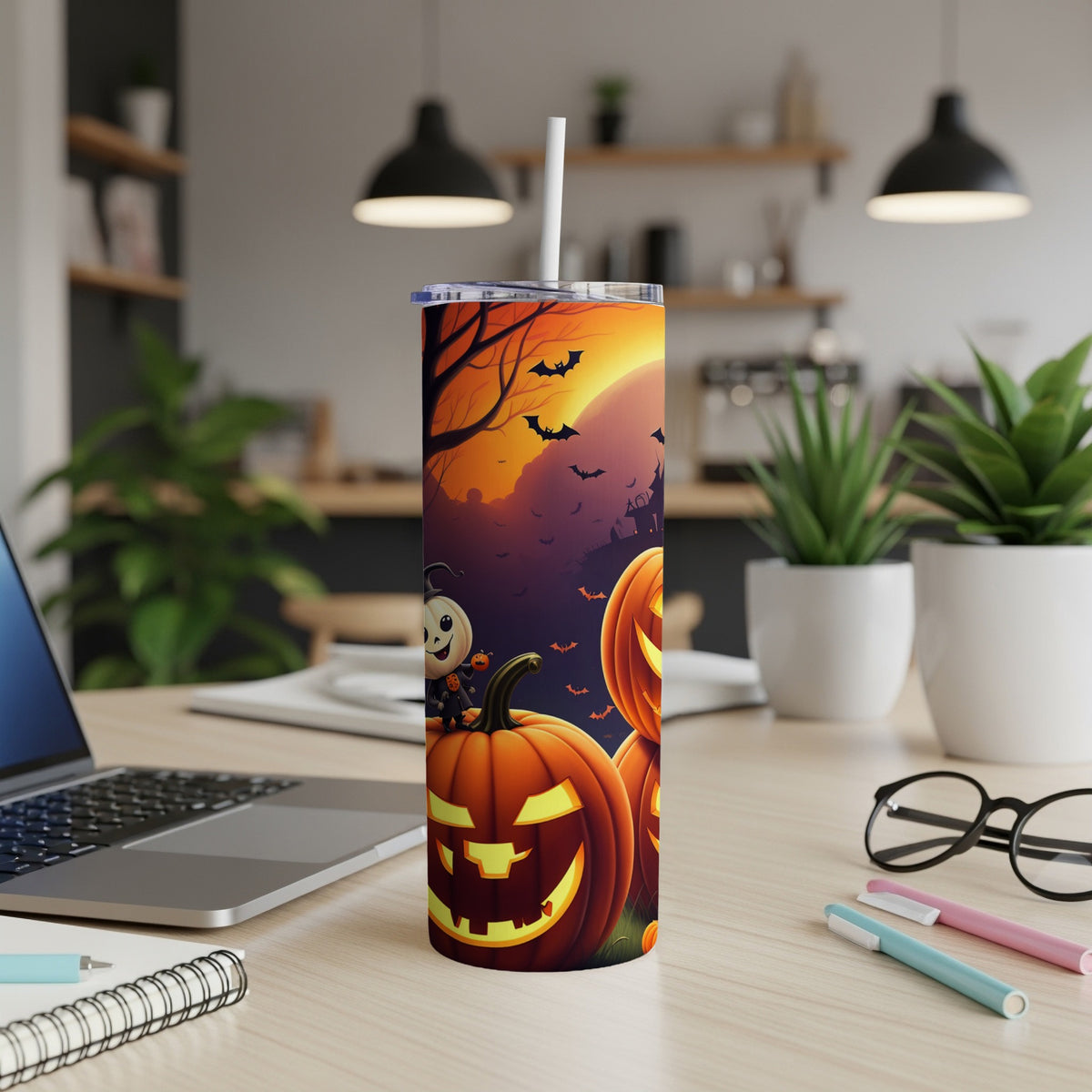 Halloween tumbler with pumpkins, a ghost, bats, and a full moon on a desk.