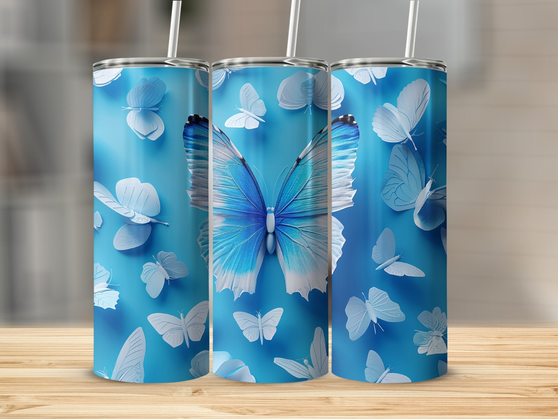 Three blue tumblers with white butterflies on a wooden surface.