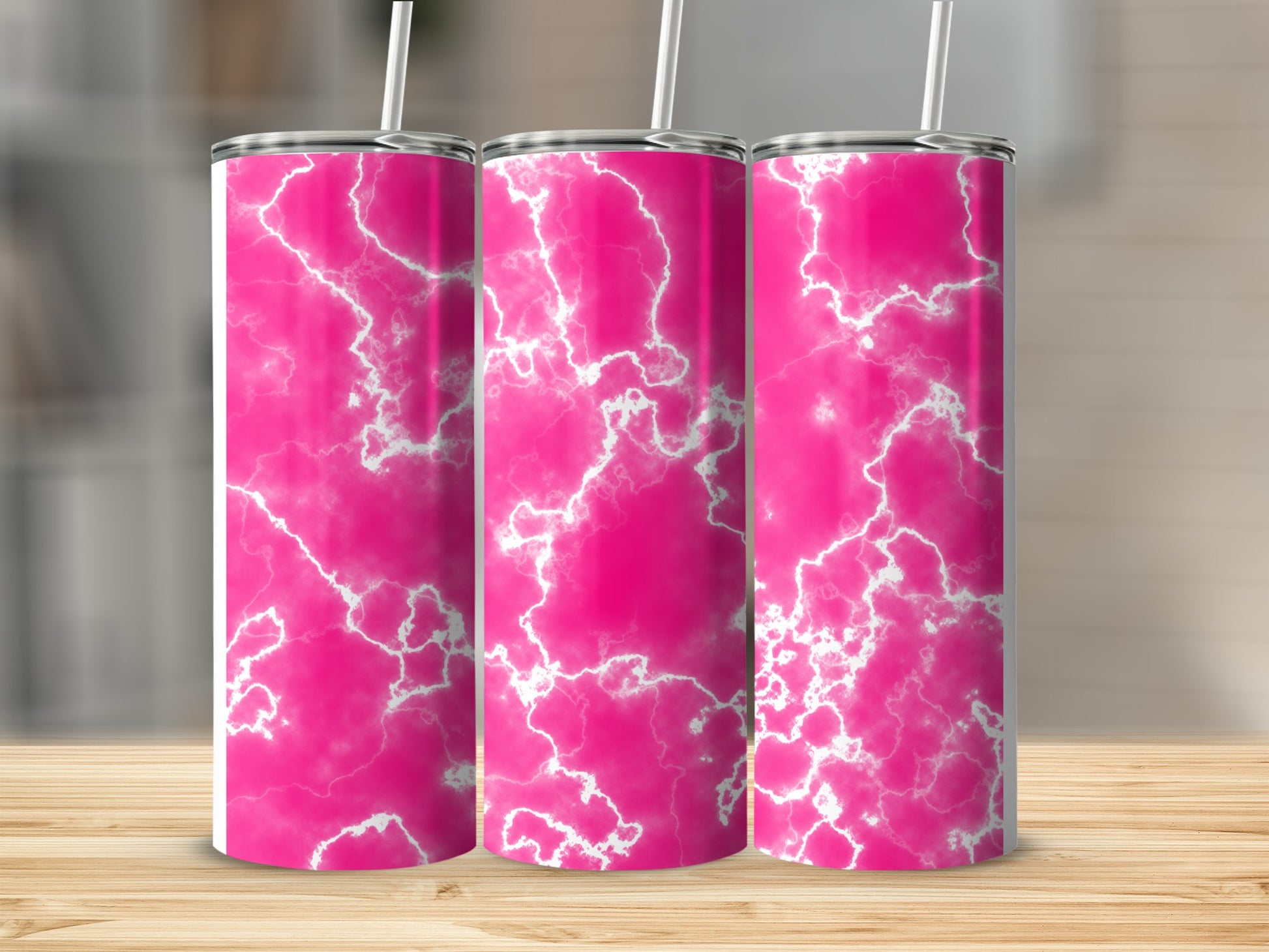 Three pink marble patterned tumblers with white straws on a wooden surface.