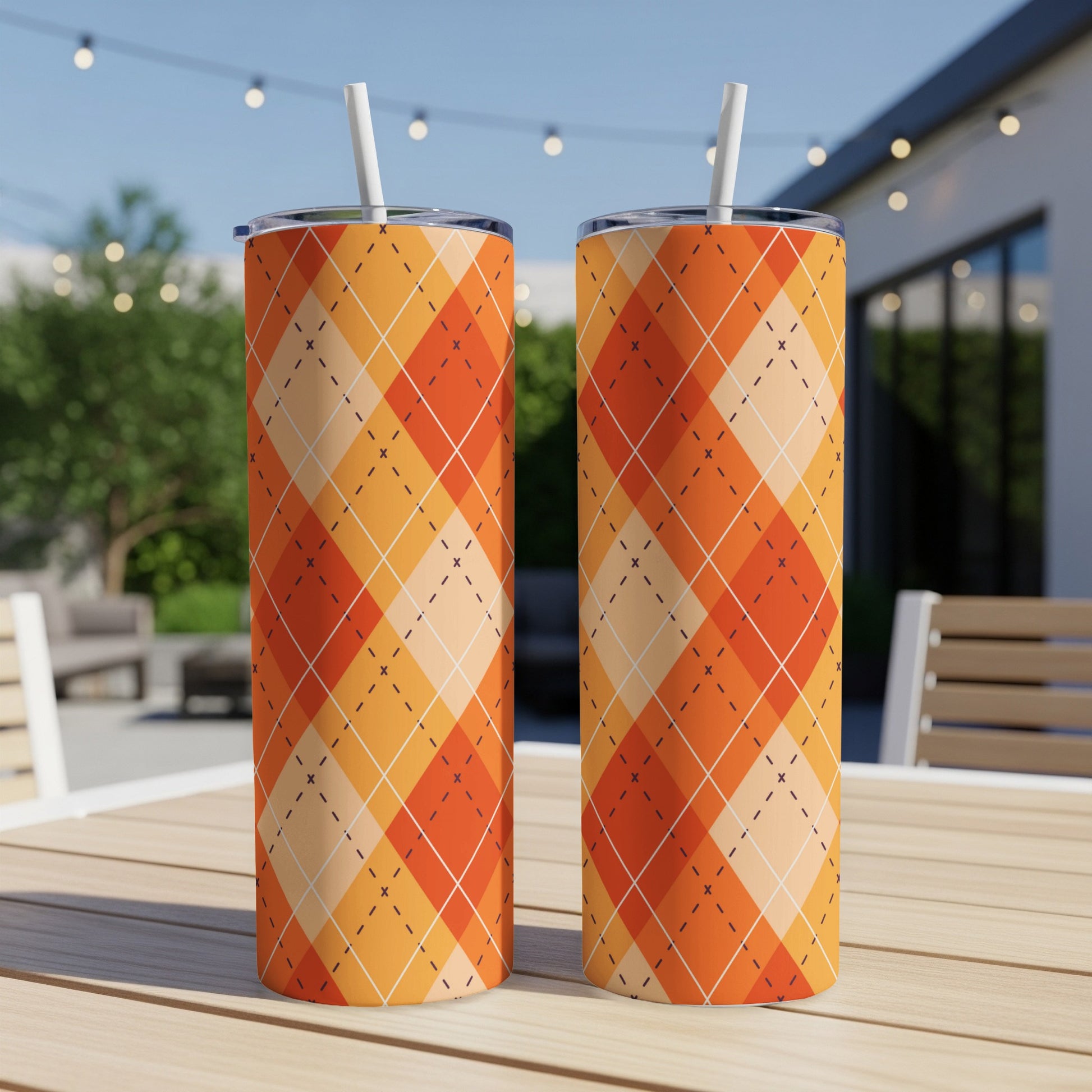 Two tall tumblers with an orange argyle pattern sit on a table.