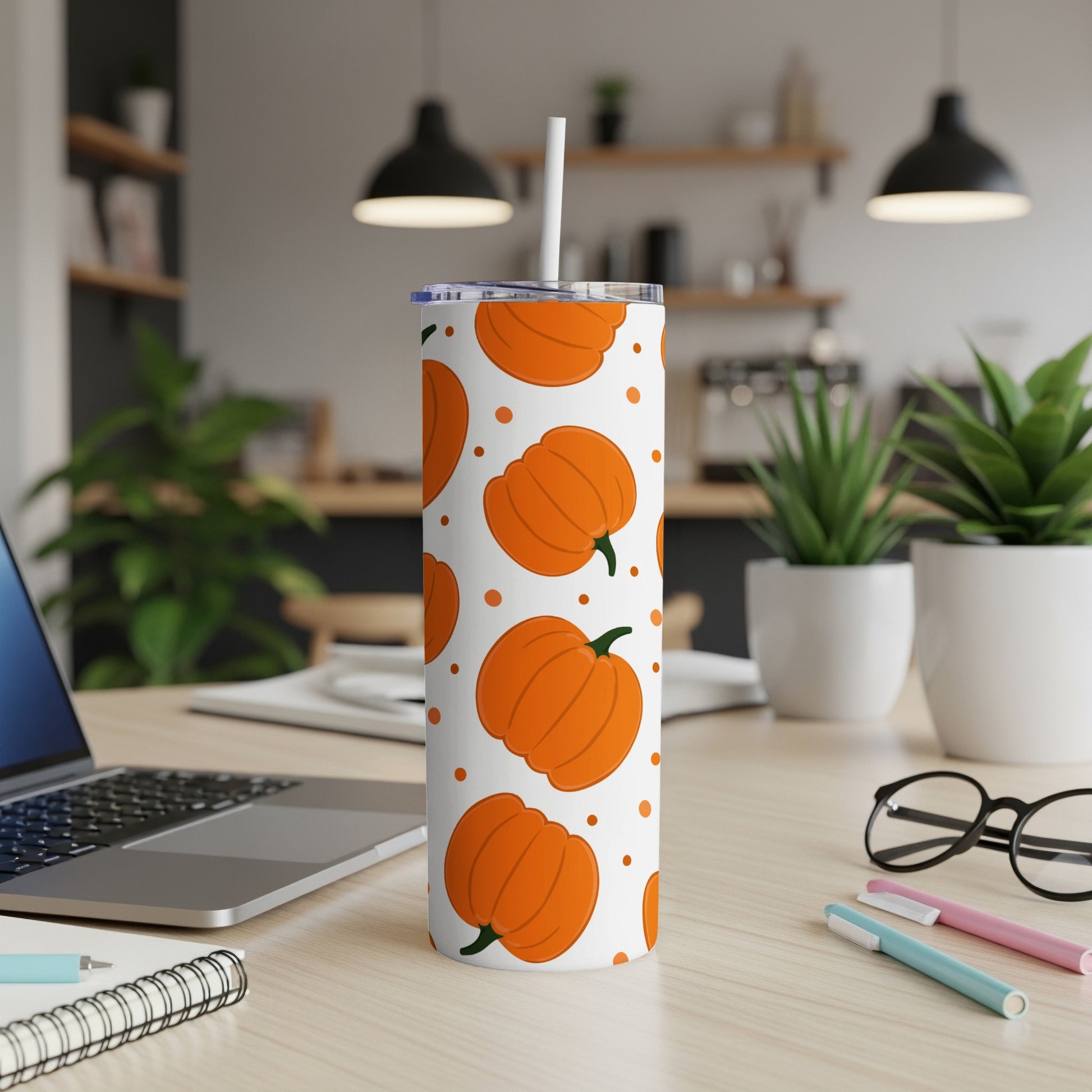 White tumbler with orange pumpkins pattern and a straw.
