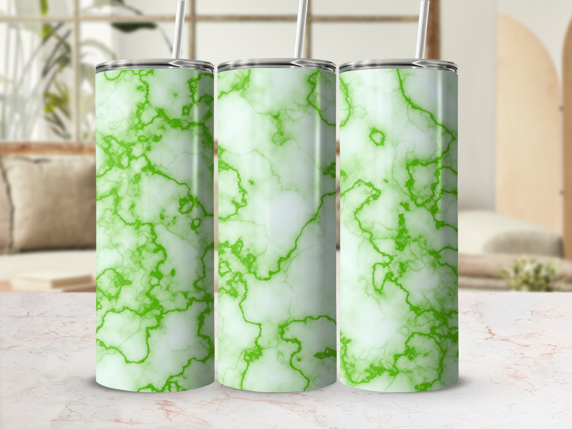 Three green marble tumblers with straws on a patterned surface.