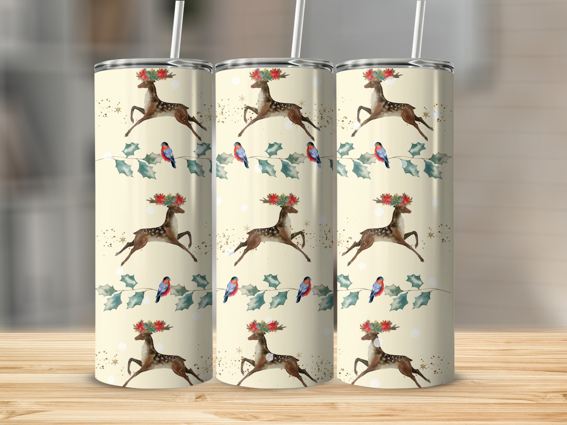 Three tumblers with a Christmas deer and bird pattern on a wooden surface.