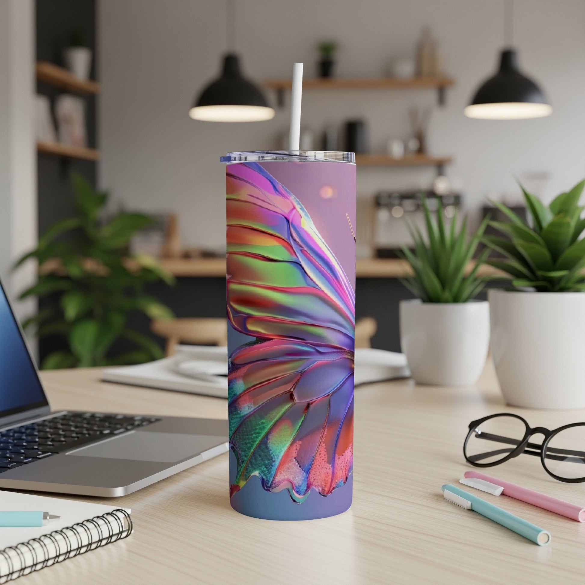 Iridescent butterfly wing tumbler with straw on desk.