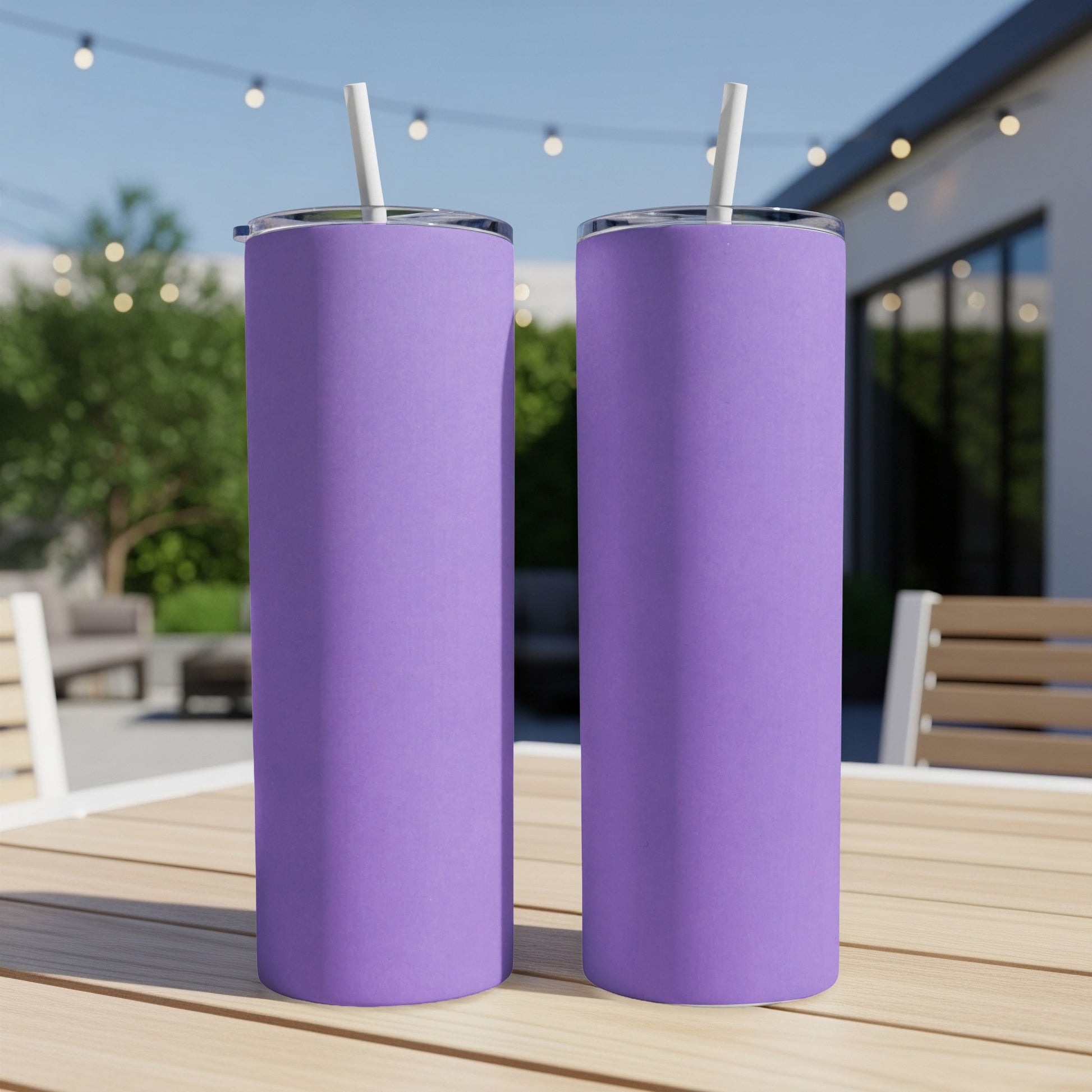 Two plain purple tumblers with white straws sit on a wooden table.
