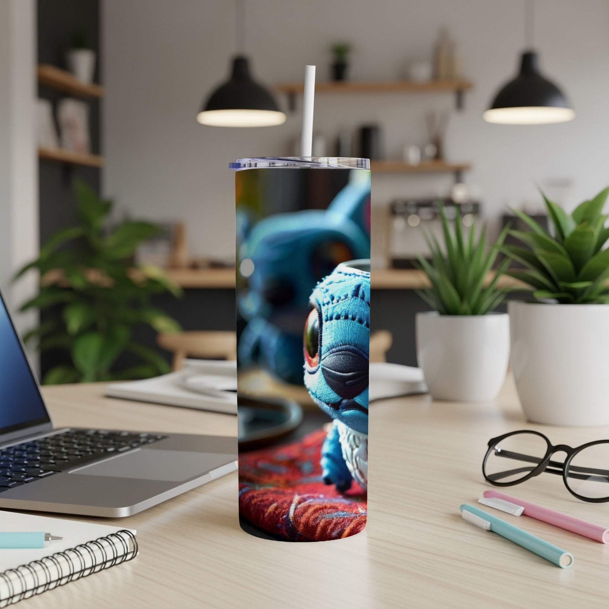 Stitch character on a tumbler with a straw, on a desk with laptop.
