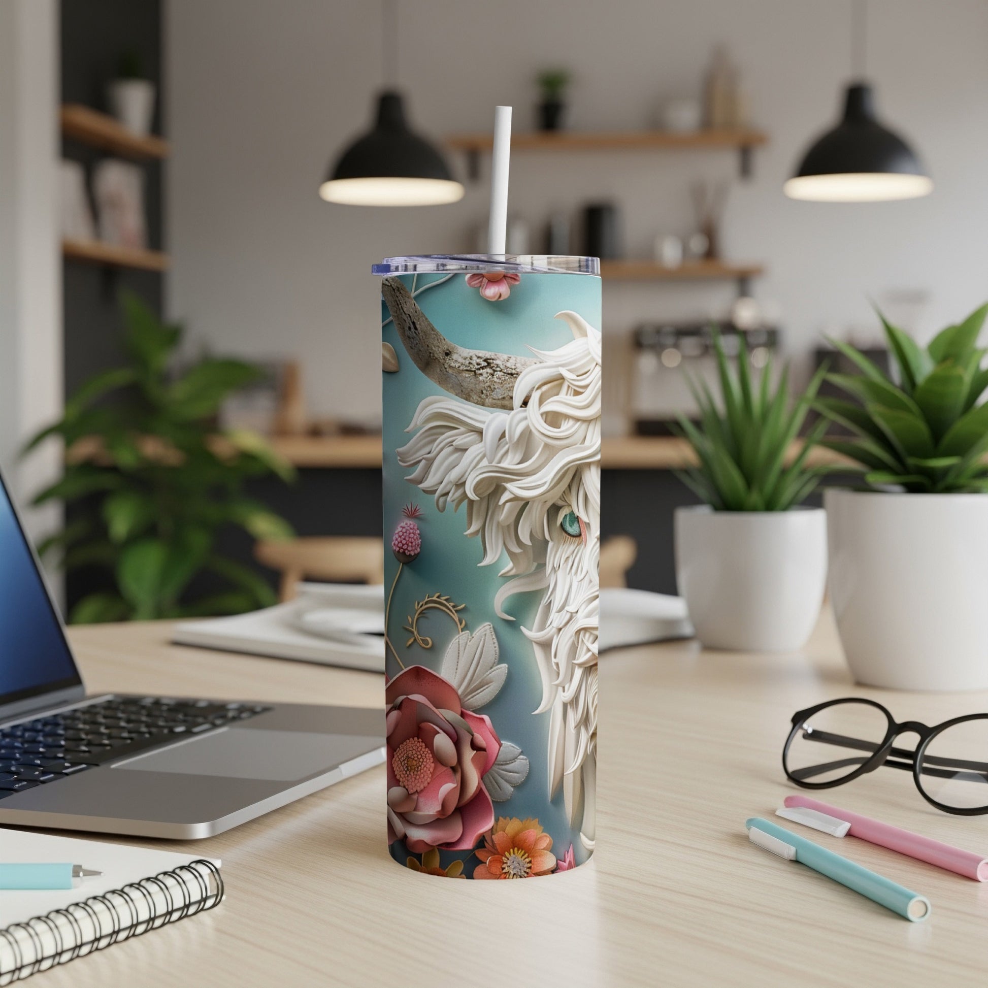 White Highland cow artwork on a teal tumbler with flowers, on a desk.