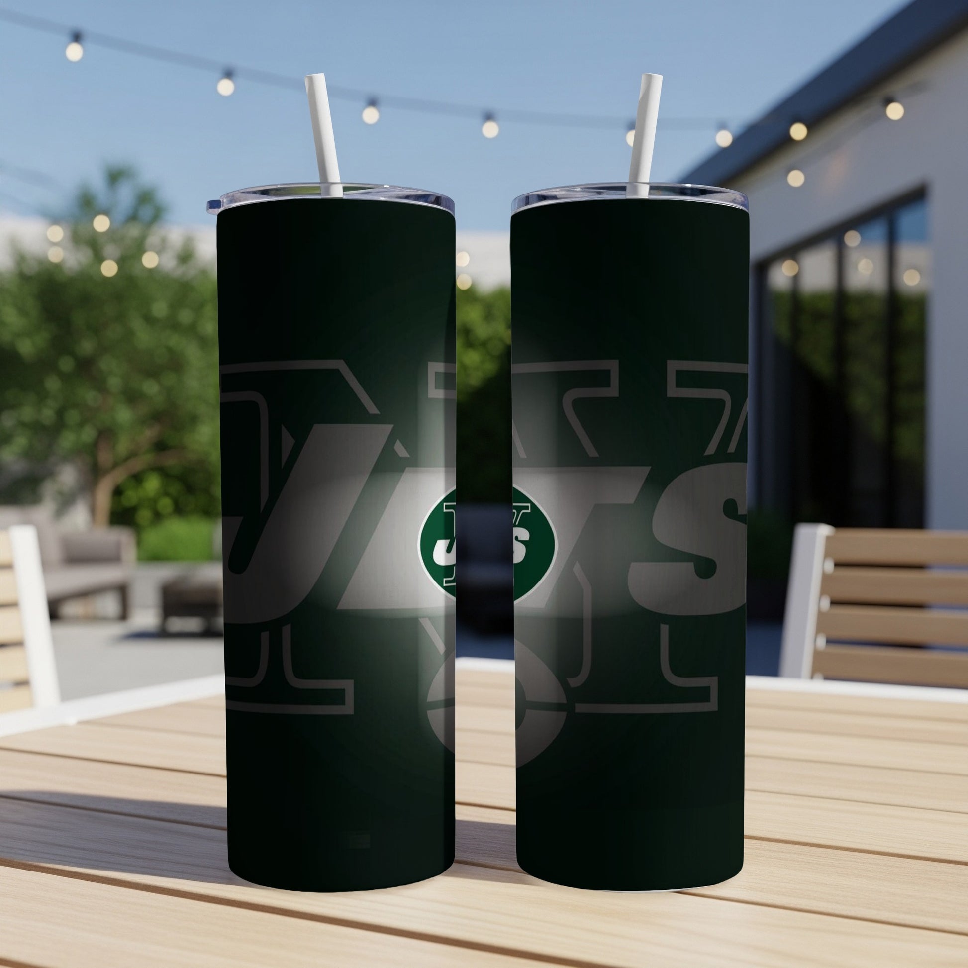 Two green New York Jets tumblers with straws on a wooden table outdoors.