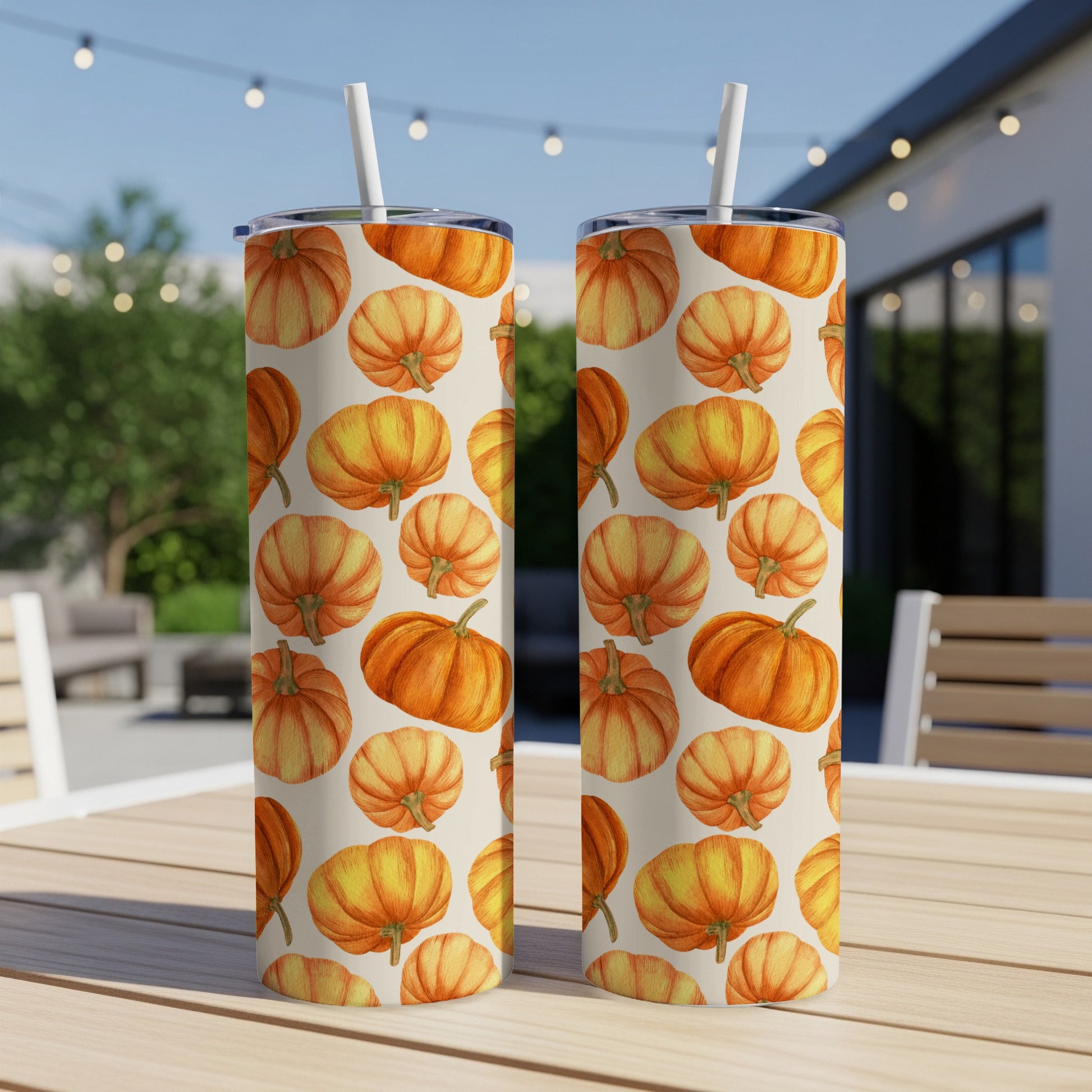 Two tumblers with a repeating pattern of orange pumpkins on a table.