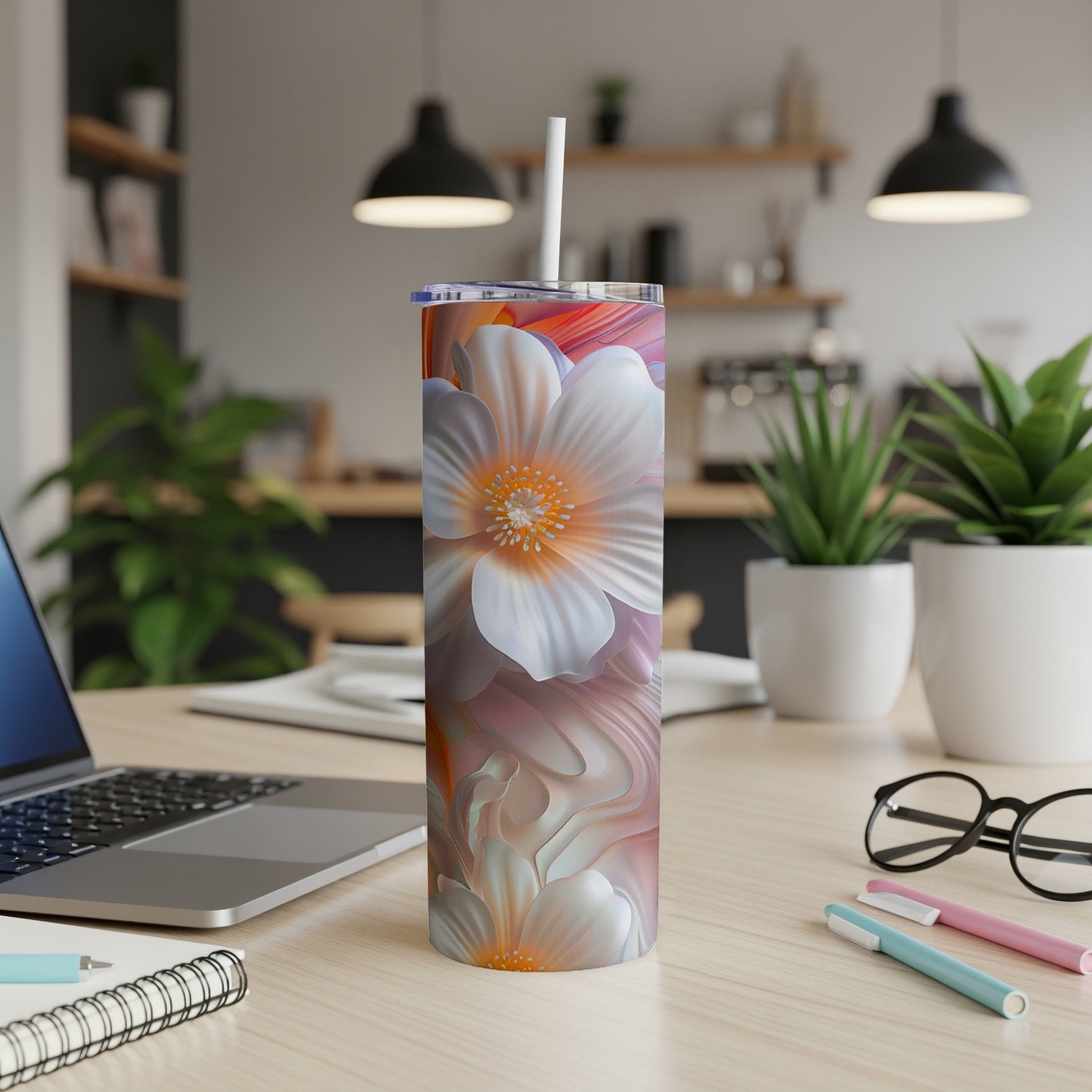 White floral pattern on a white tumbler with a straw on a desk.