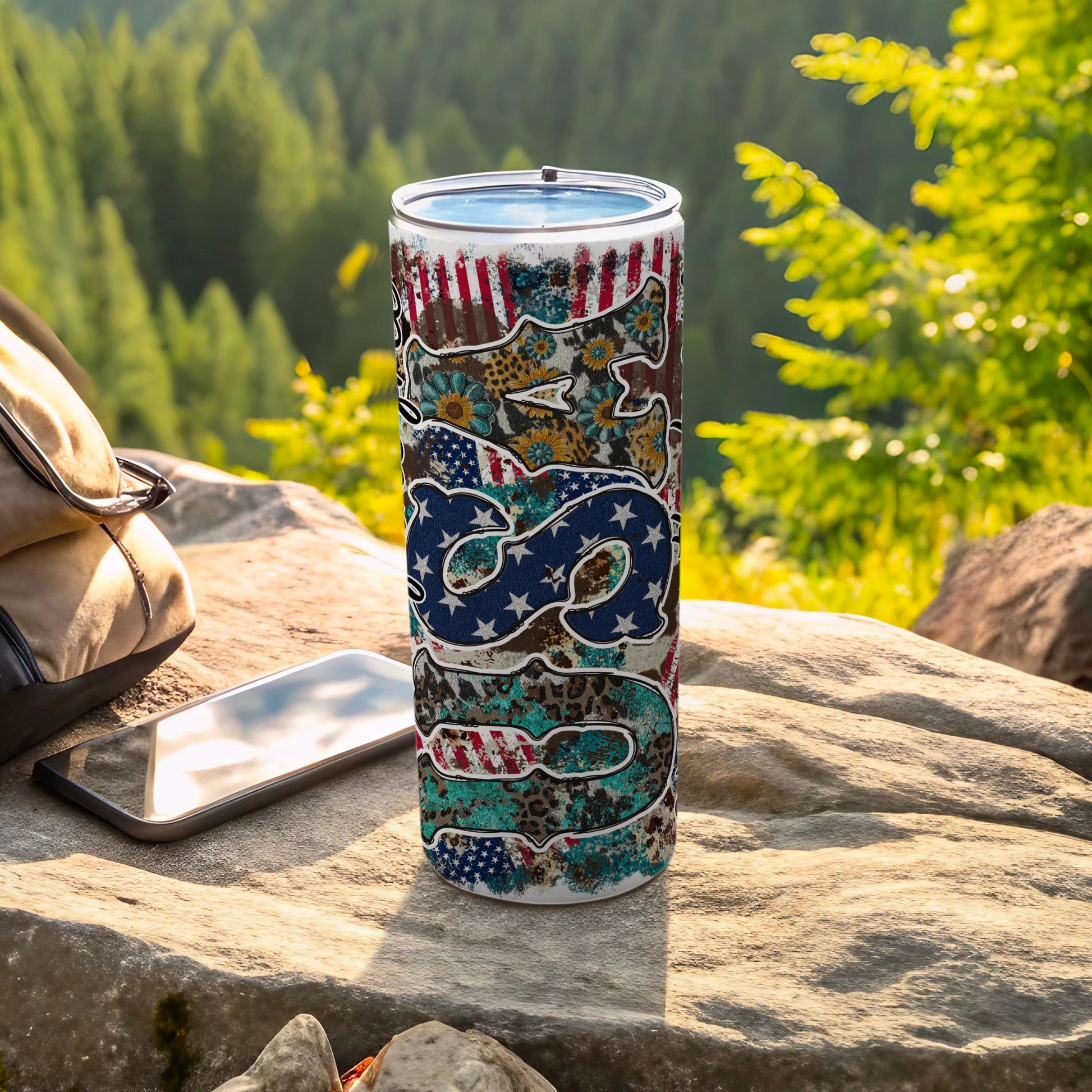 Patriotic USA flag and animal print tumbler on a rock outdoors.