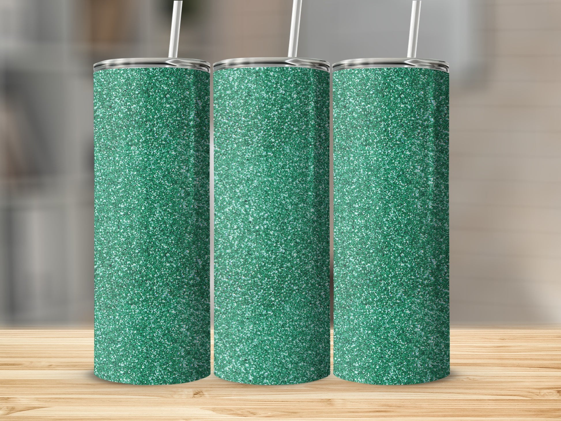 Three green glitter tumblers with straws stand on a wooden surface.