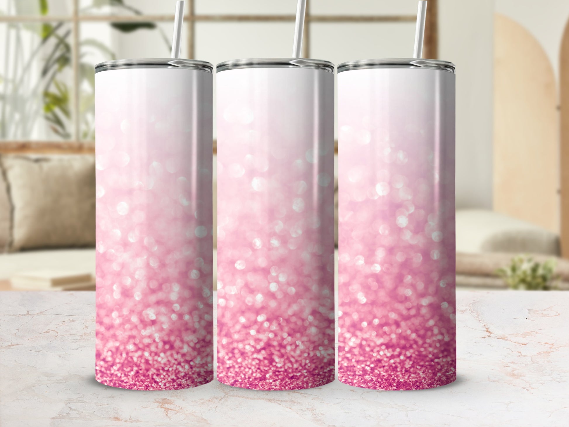Three pink glitter tumblers with straws on a marble surface.