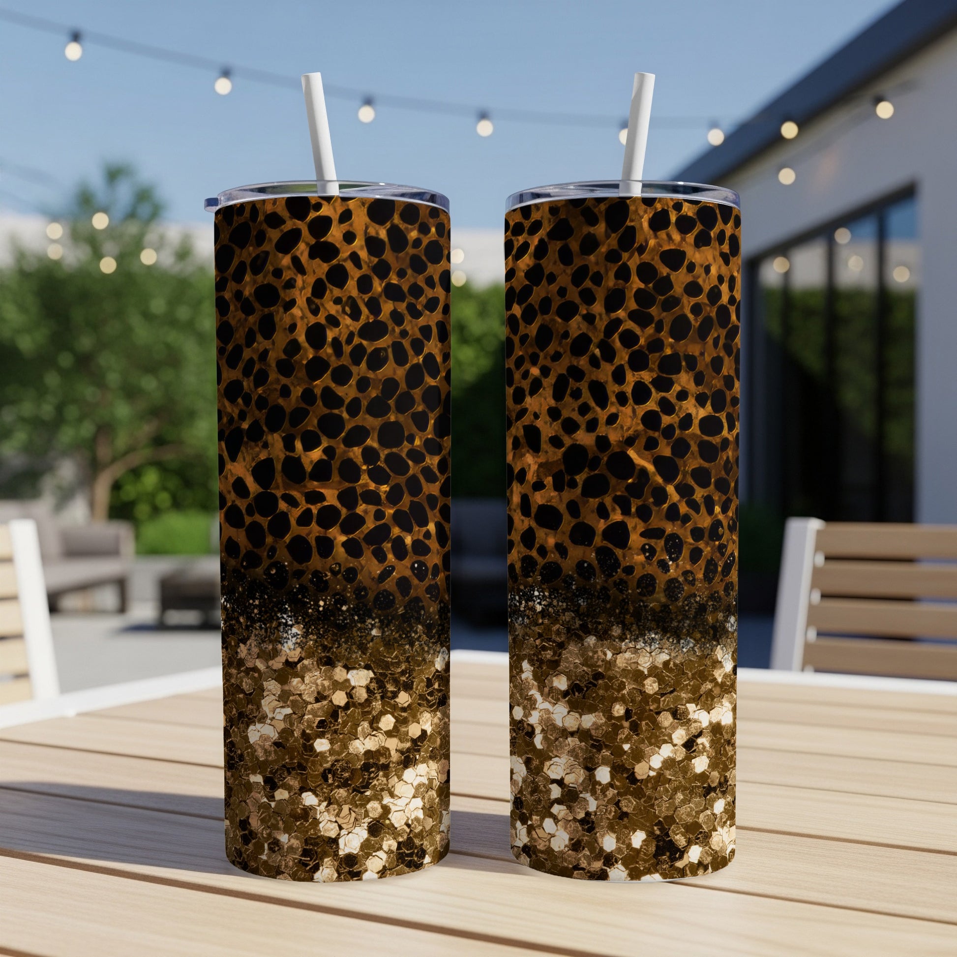 Leopard print and glitter design on two tall tumblers on an outdoor table.