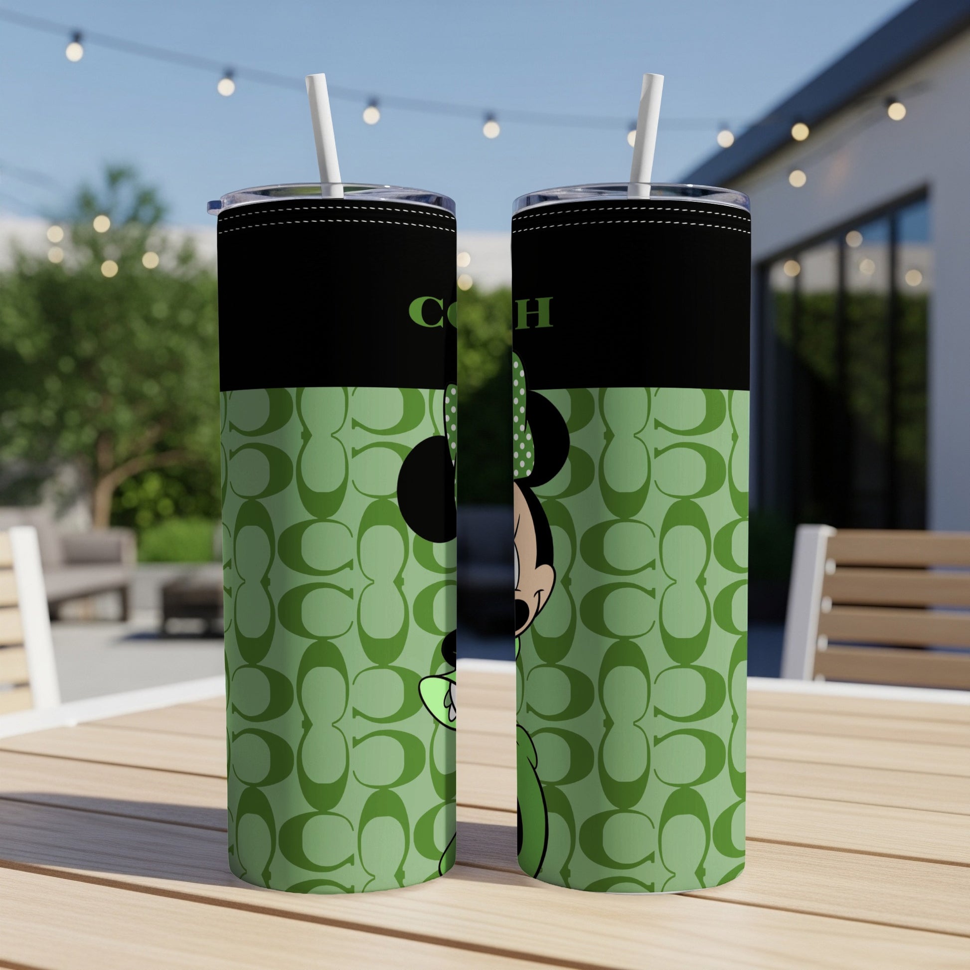 Two black tumblers with Minnie Mouse and a Coach logo on a green pattern.